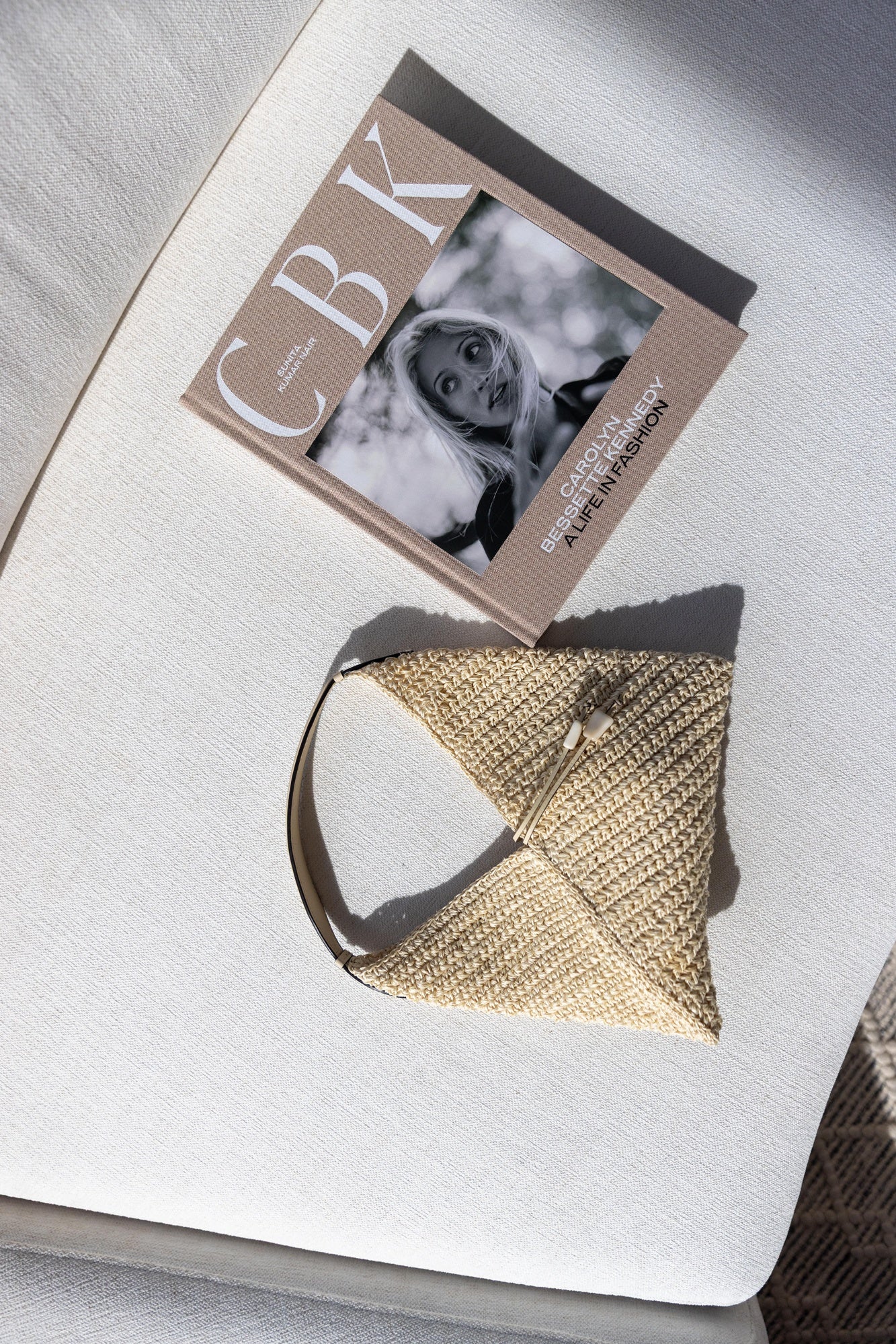 Hunting season bag next to CBK: Carolyn Bessette Kennedy Coffee table book on a white sofa.