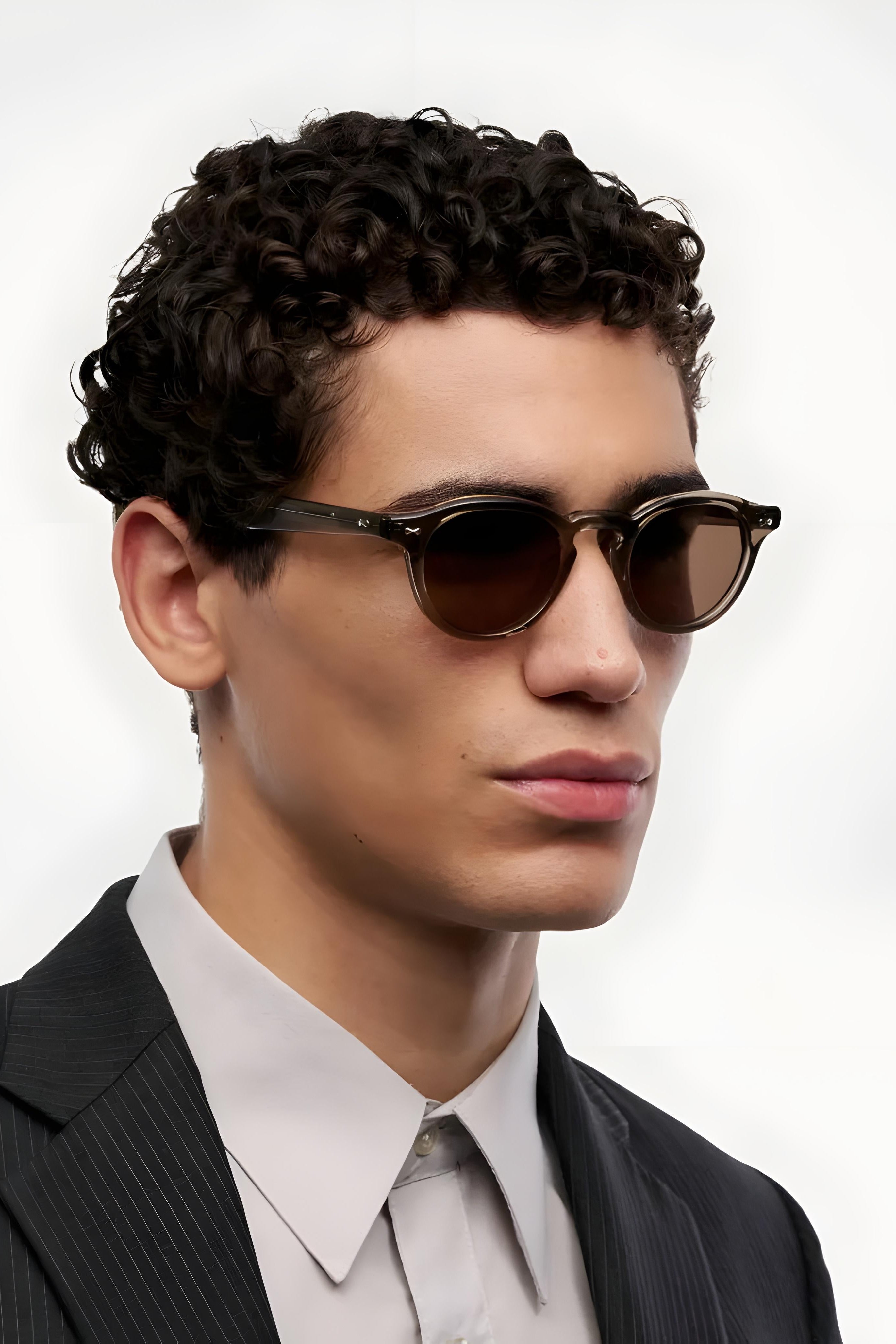 Man wearing sunglasses and a suit against a white background