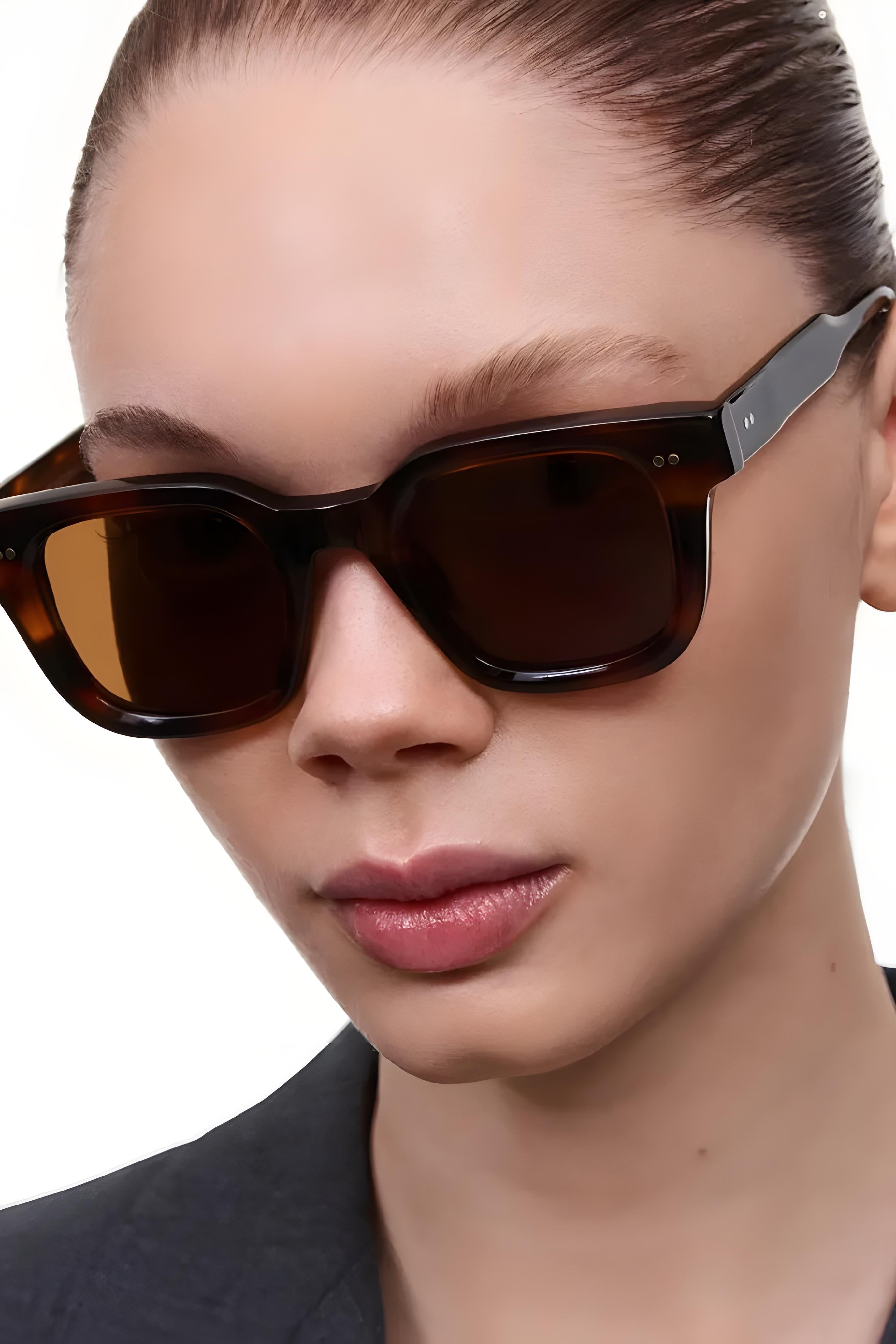 Close-up of a person wearing dark sunglasses with a neutral background