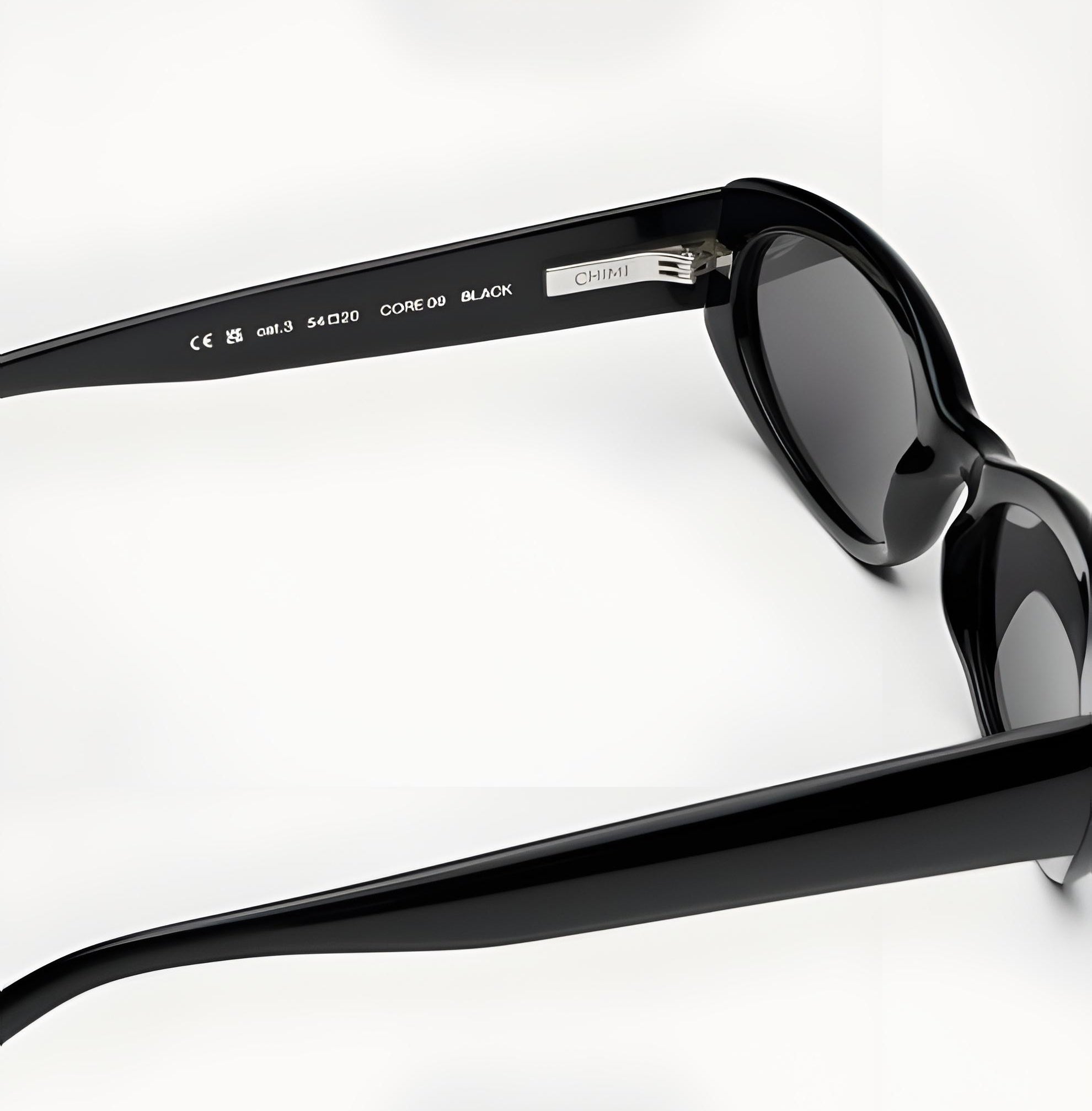 Black sunglasses with 'Chanel' branding on a light gray background