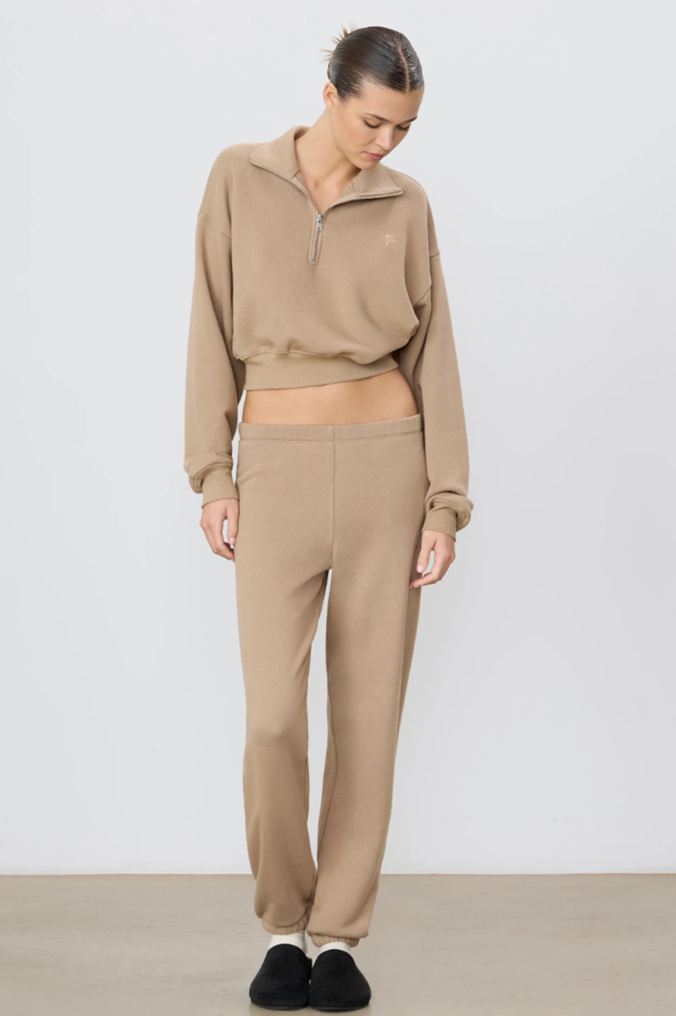 Person wearing a beige tracksuit against a white background