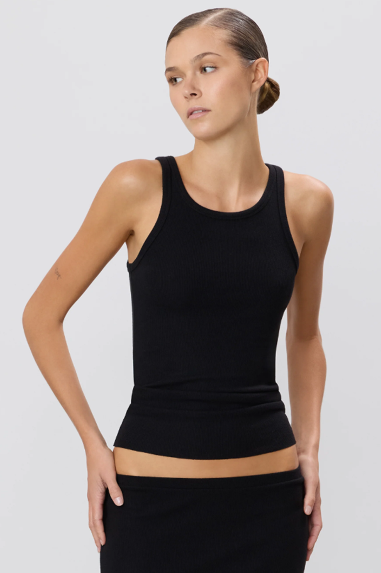 Woman wearing a black tank top against a plain background