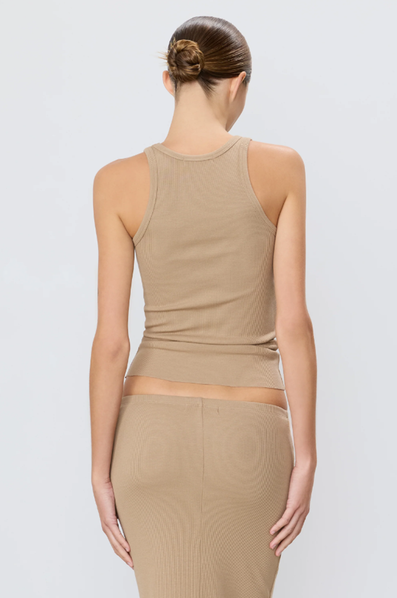 back of model wearing a beige tank top and skirt set on a light gray background