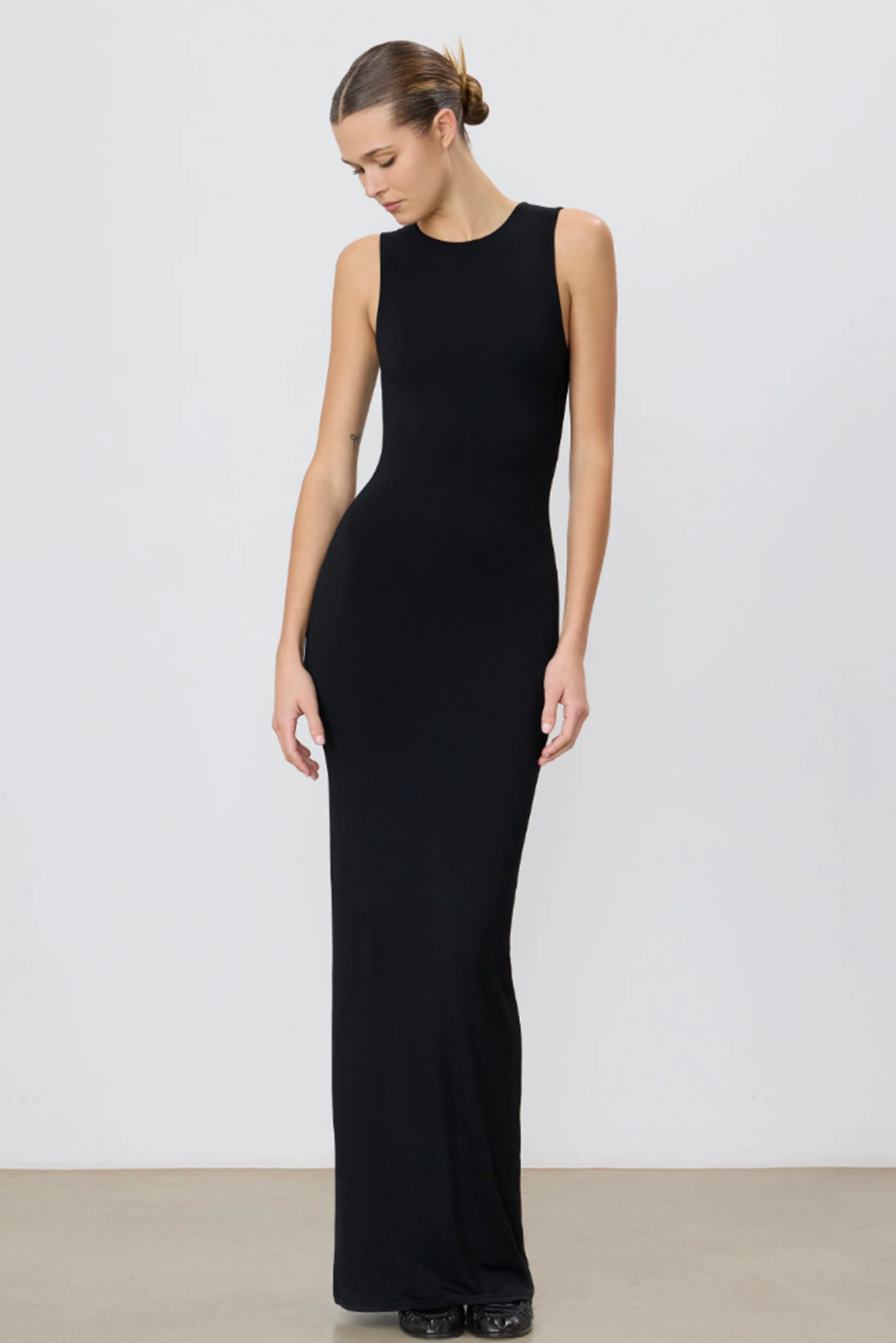 Woman wearing a black sleeveless gown against a white background