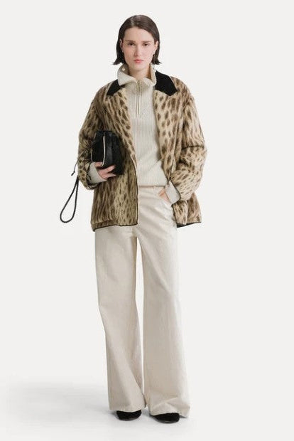 Model wearing the Forte Forte Royal Leopard Jacquard Double Breasted Coat in Giallo Oro with cream wide-leg trousers and a black handbag, full-length view