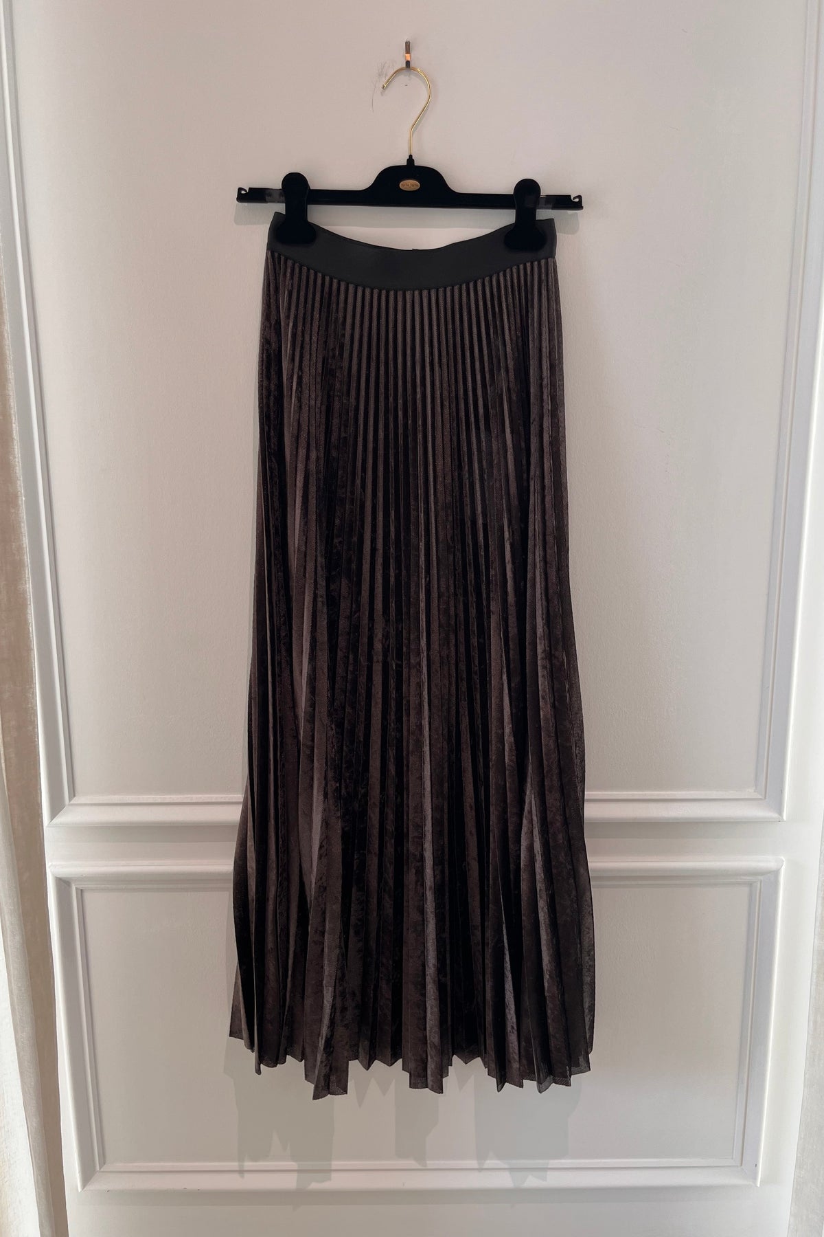 Forte Forte Soleil Plisse Flocked Stretch Tulle Midi Skirt in Fondant, a dark brown accordion-pleated sheer burnout midi skirt with elastic waist on a hanger
