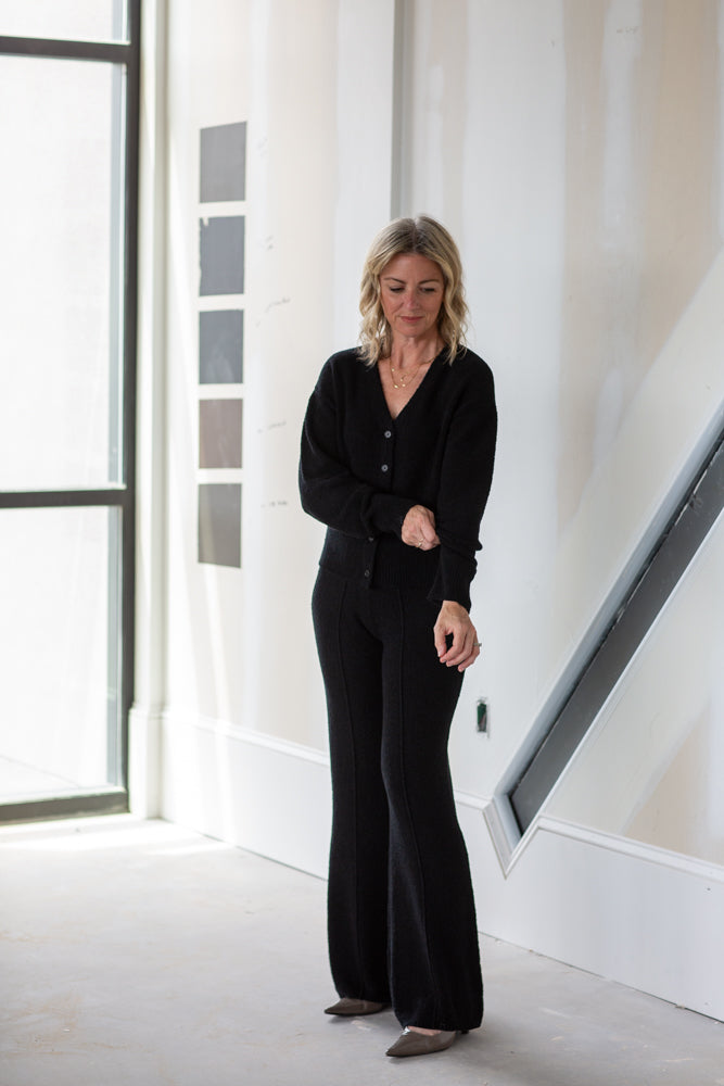 Woman in a black outfit standing in a modern interior setting