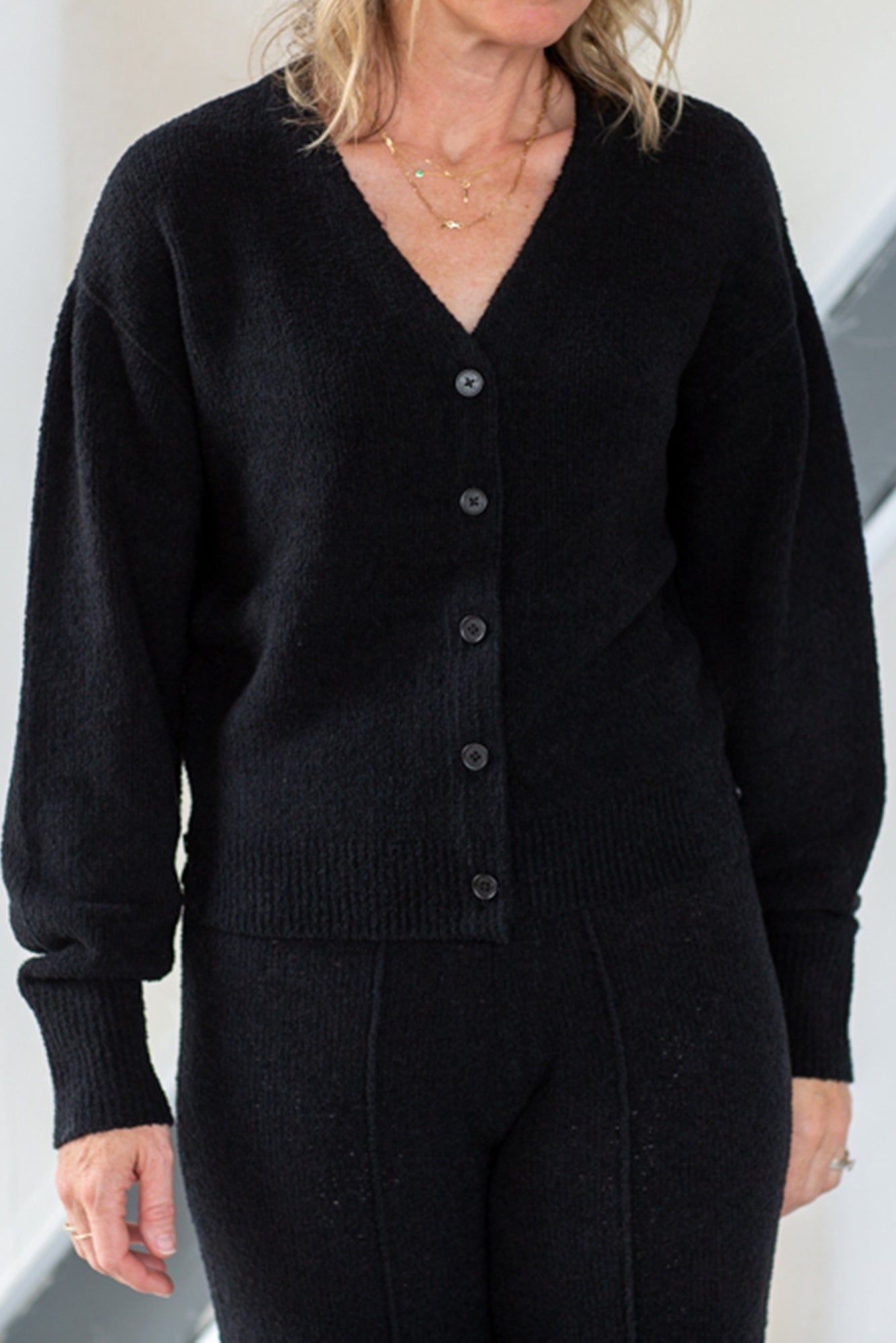 Person wearing a black cardigan against a neutral background
