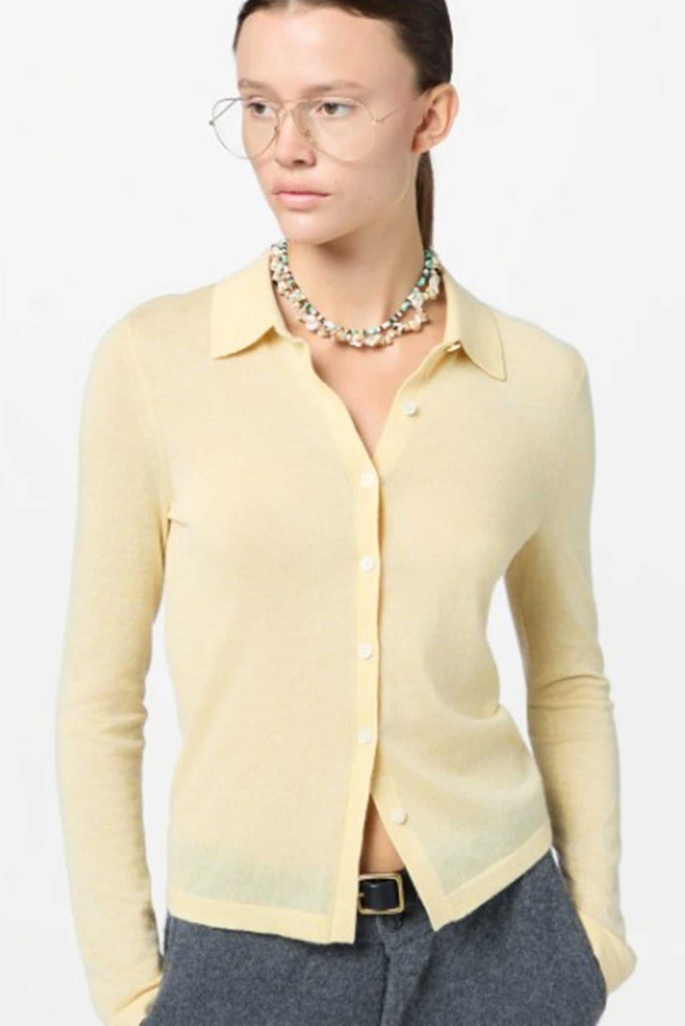 Woman wearing a light yellow button-up shirt with a plain background