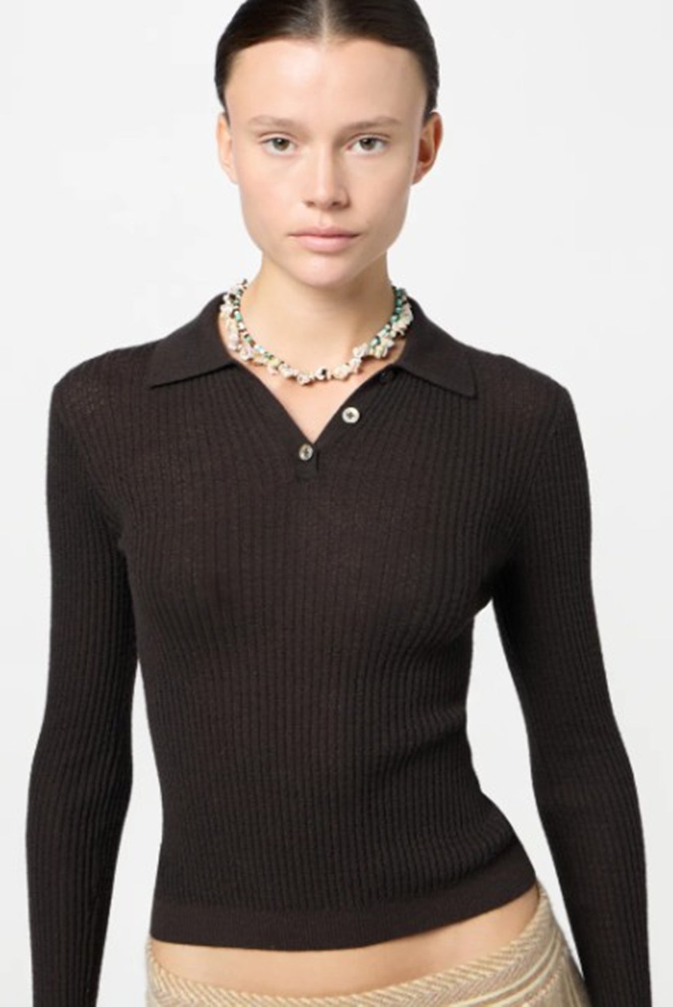 Woman wearing a black ribbed sweater with a collar on a white background