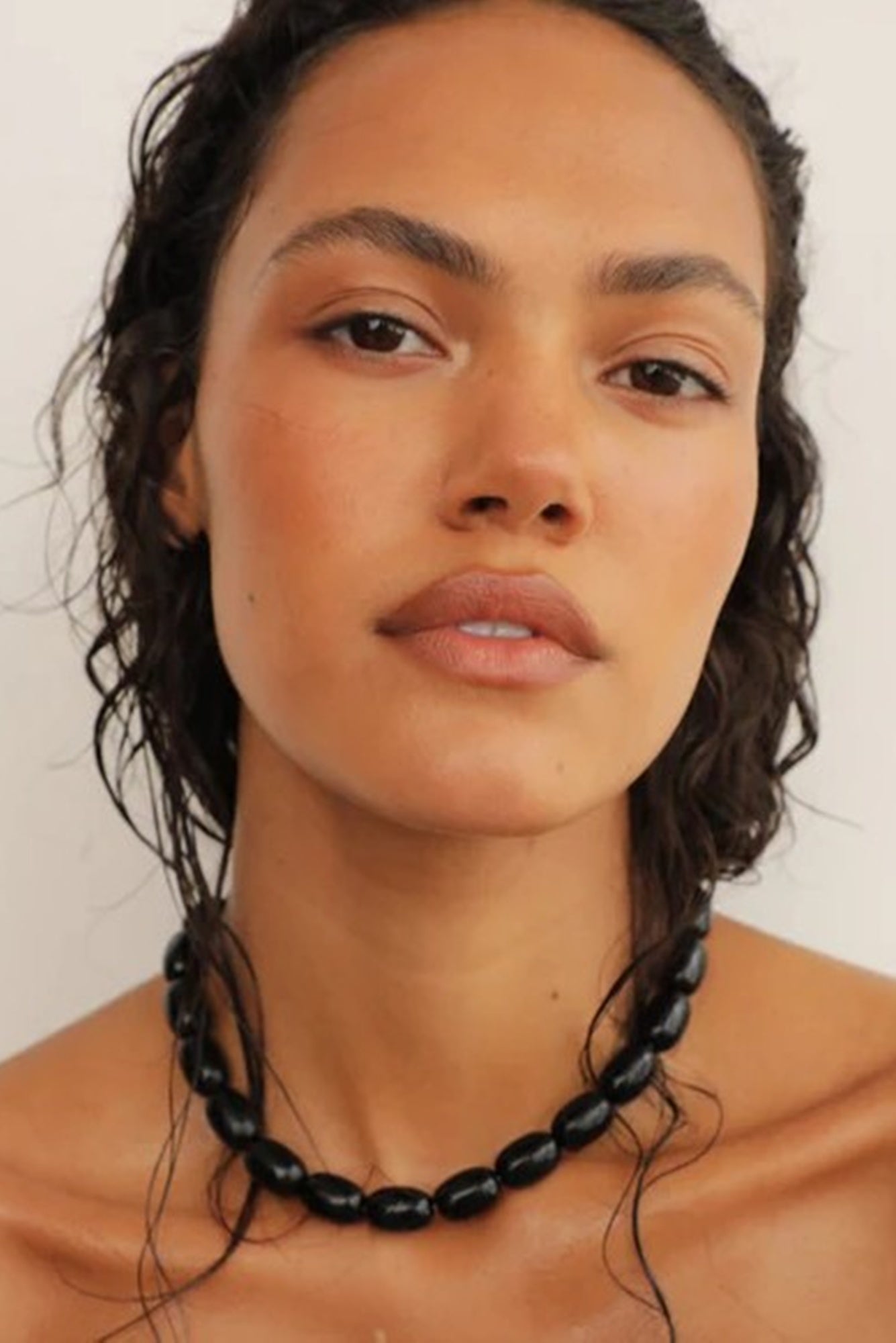 Woman wearing a black beaded necklace against a plain background