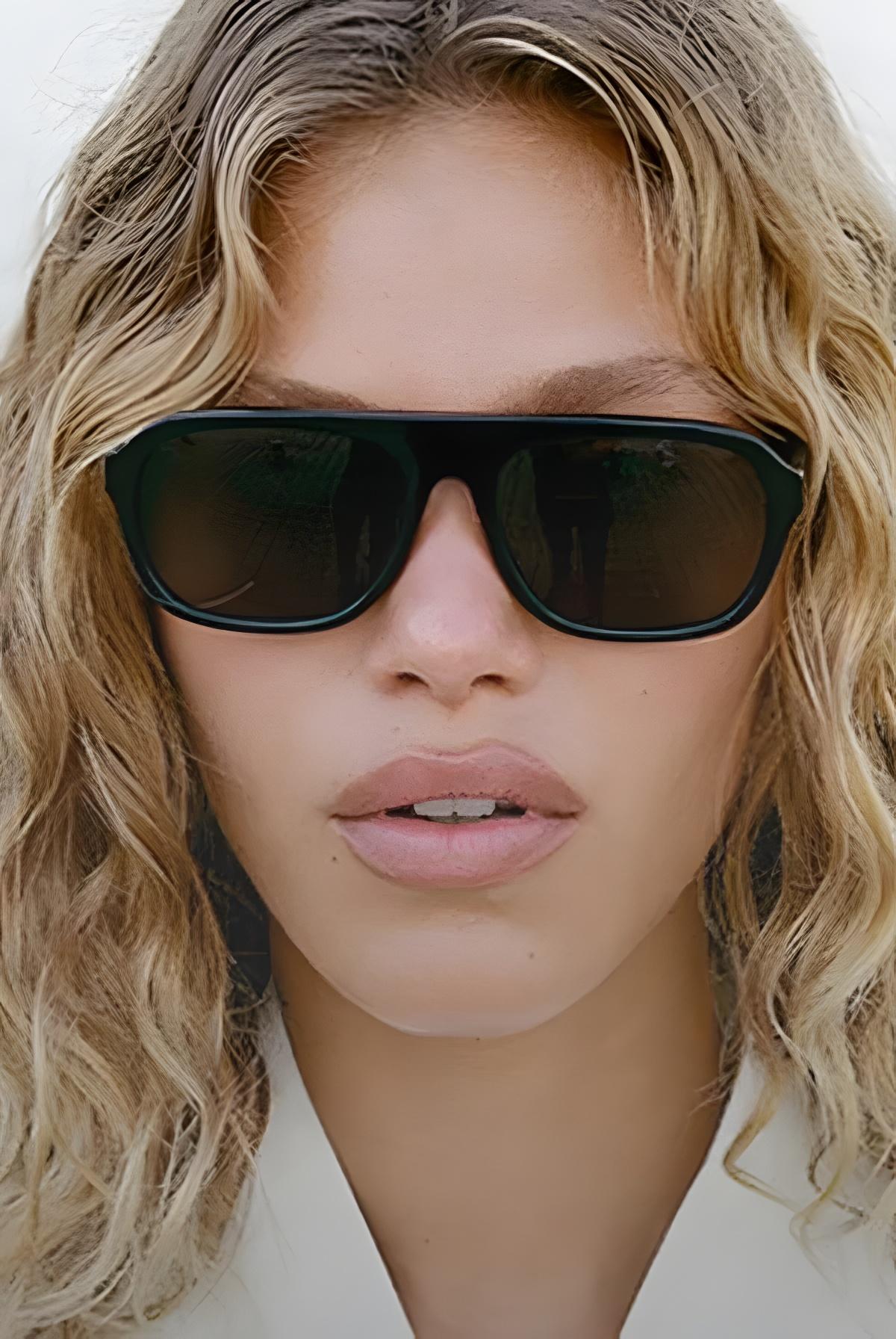 Close-up of a person wearing black sunglasses with a neutral background