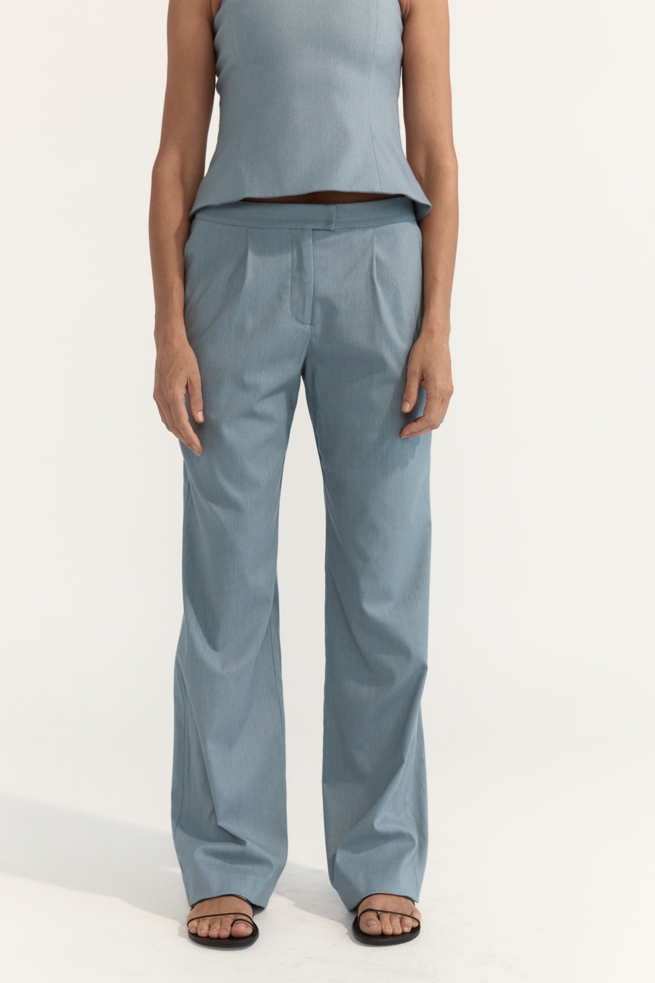 Person wearing light blue pants and a matching top on a white background