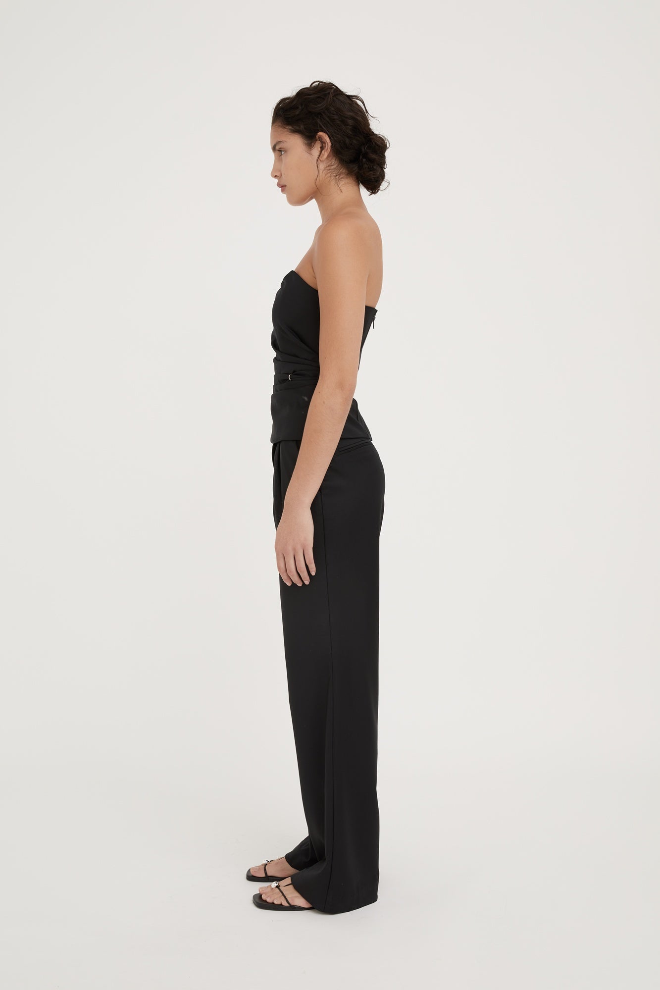 Woman wearing a black strapless jumpsuit on a white background