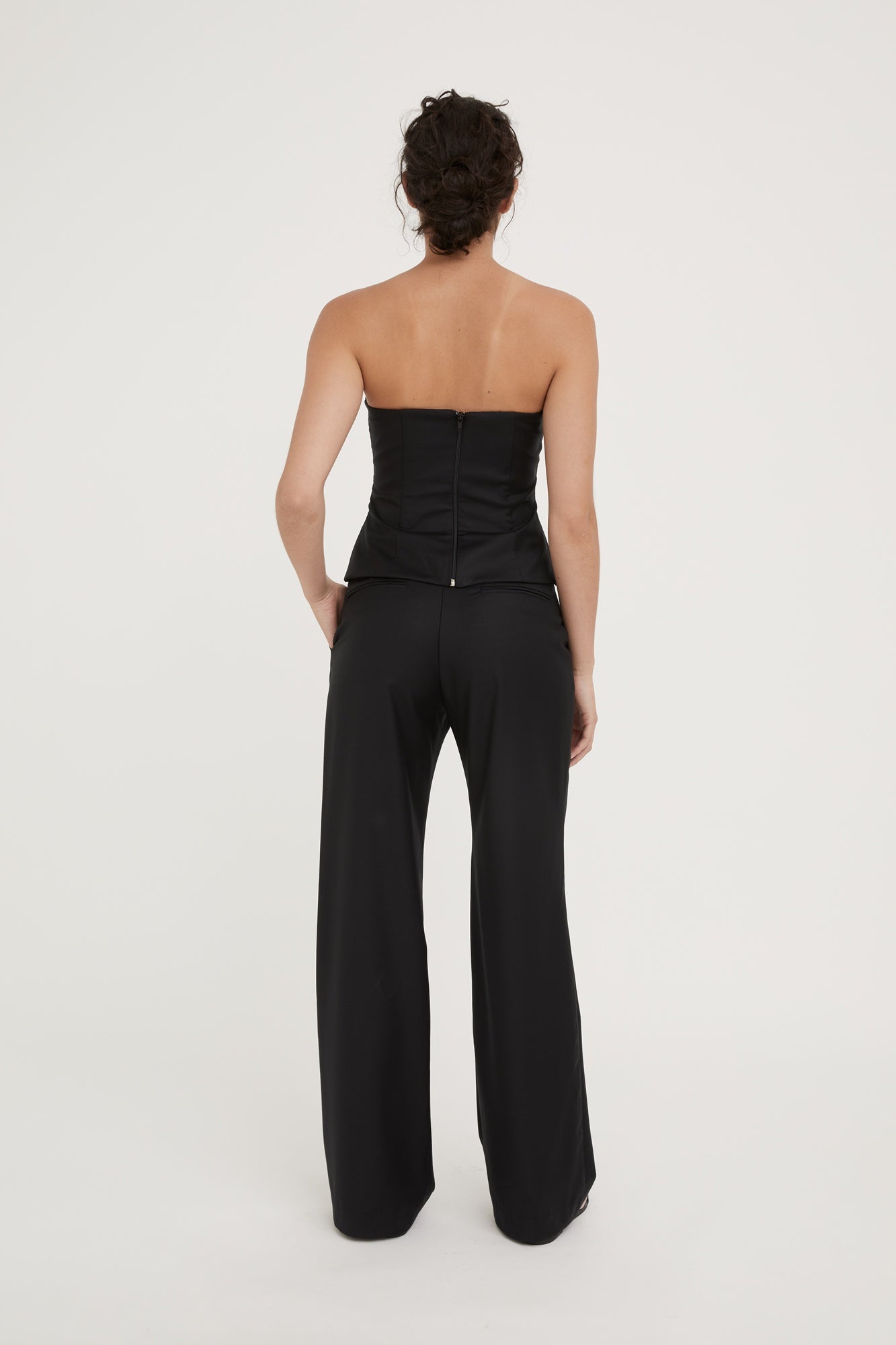 Person wearing a black strapless jumpsuit on a white background