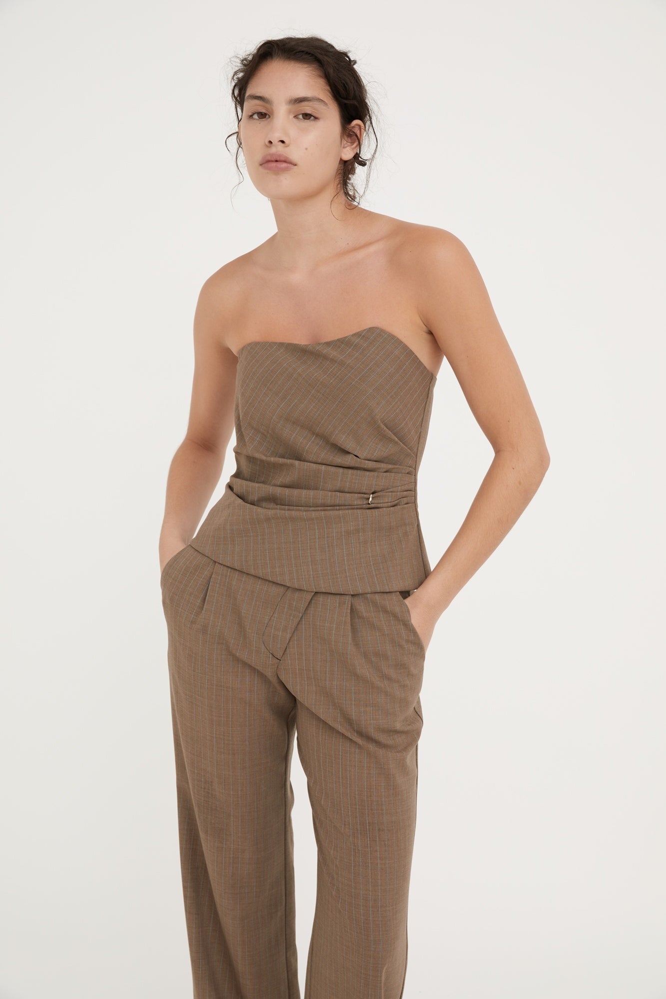 Woman wearing a brown strapless top and pants on a white background
