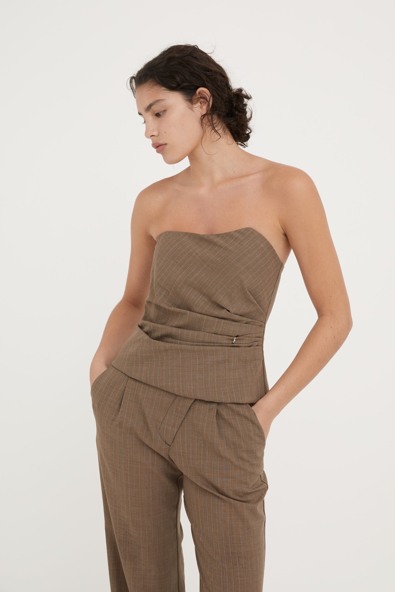 Woman wearing a brown strapless top and pants on a white background