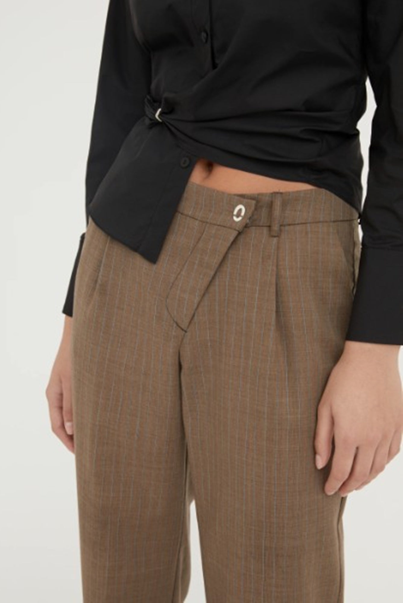 Person wearing a black shirt and brown plaid pants on a white background