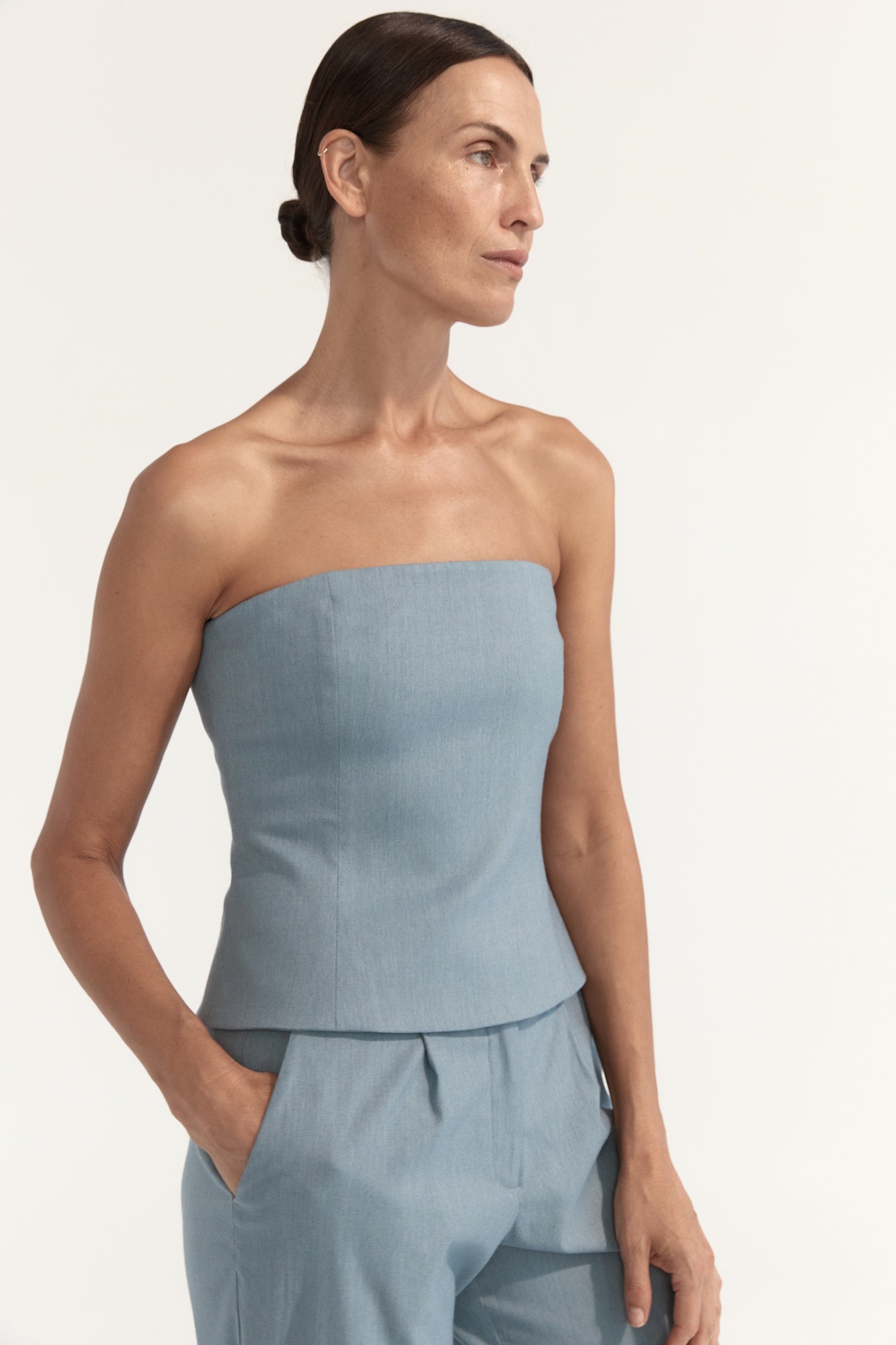 Woman wearing a light blue strapless top and skirt set on a plain background