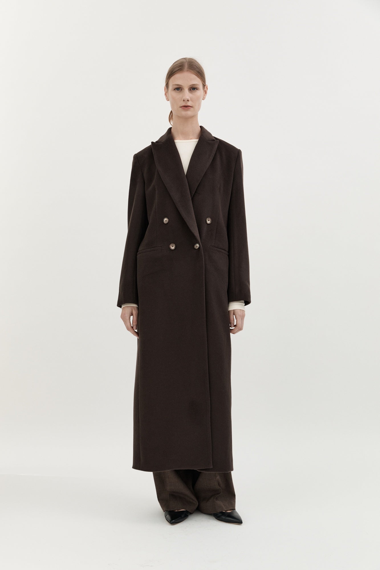 Person wearing a long dark coat on a white background