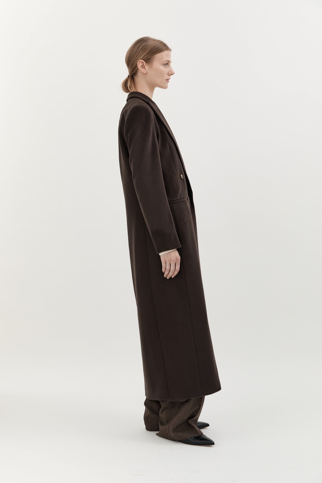 Woman wearing a long dark coat on a white background