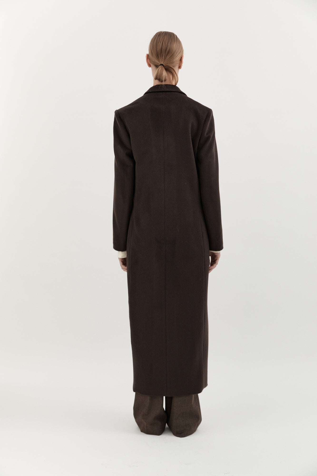 Person wearing a long dark coat on a white background