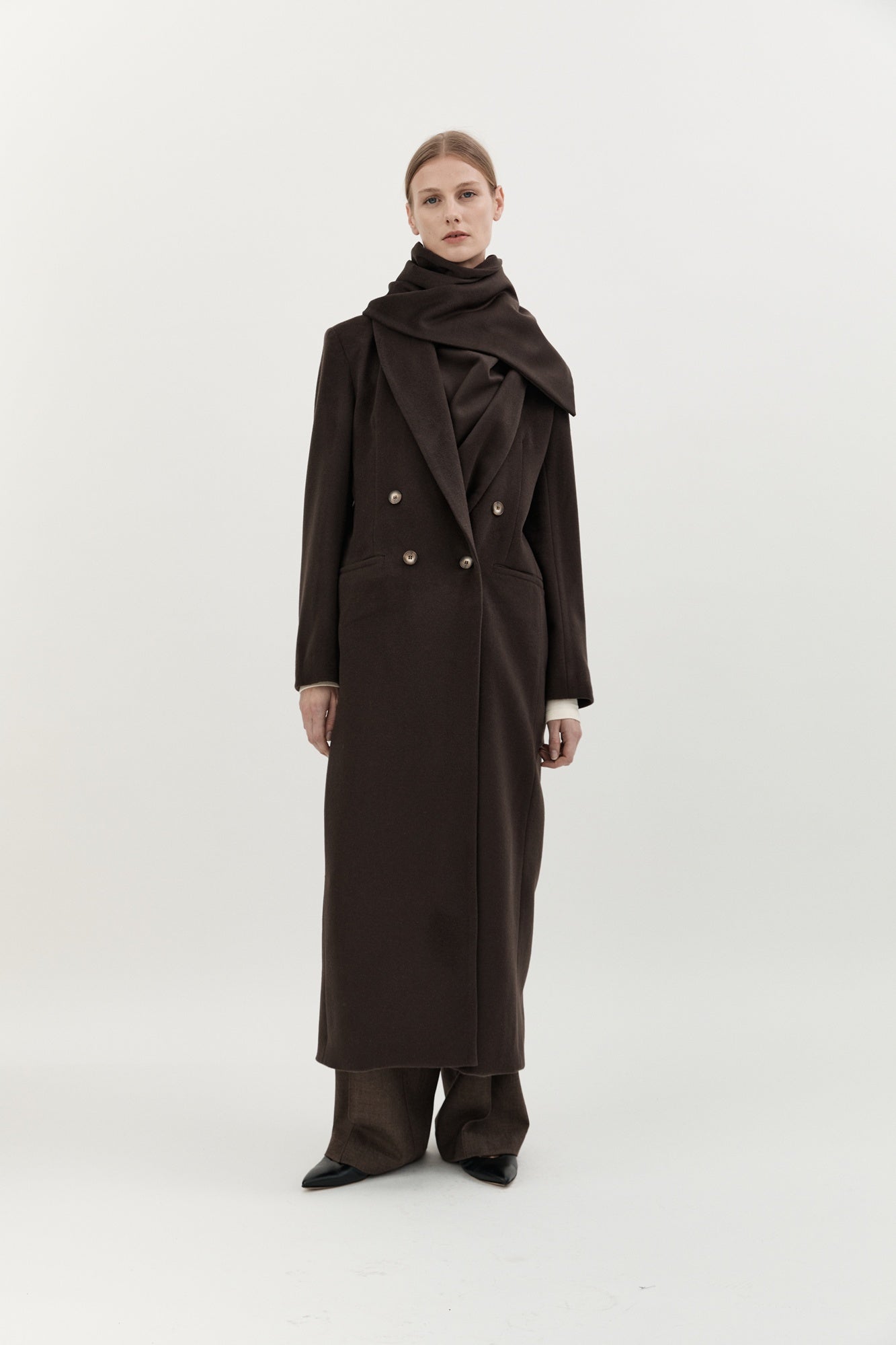 Woman wearing a long brown coat on a white background