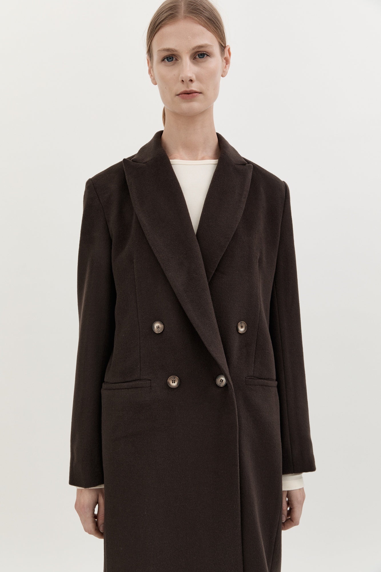 Woman wearing a dark brown coat with a white background