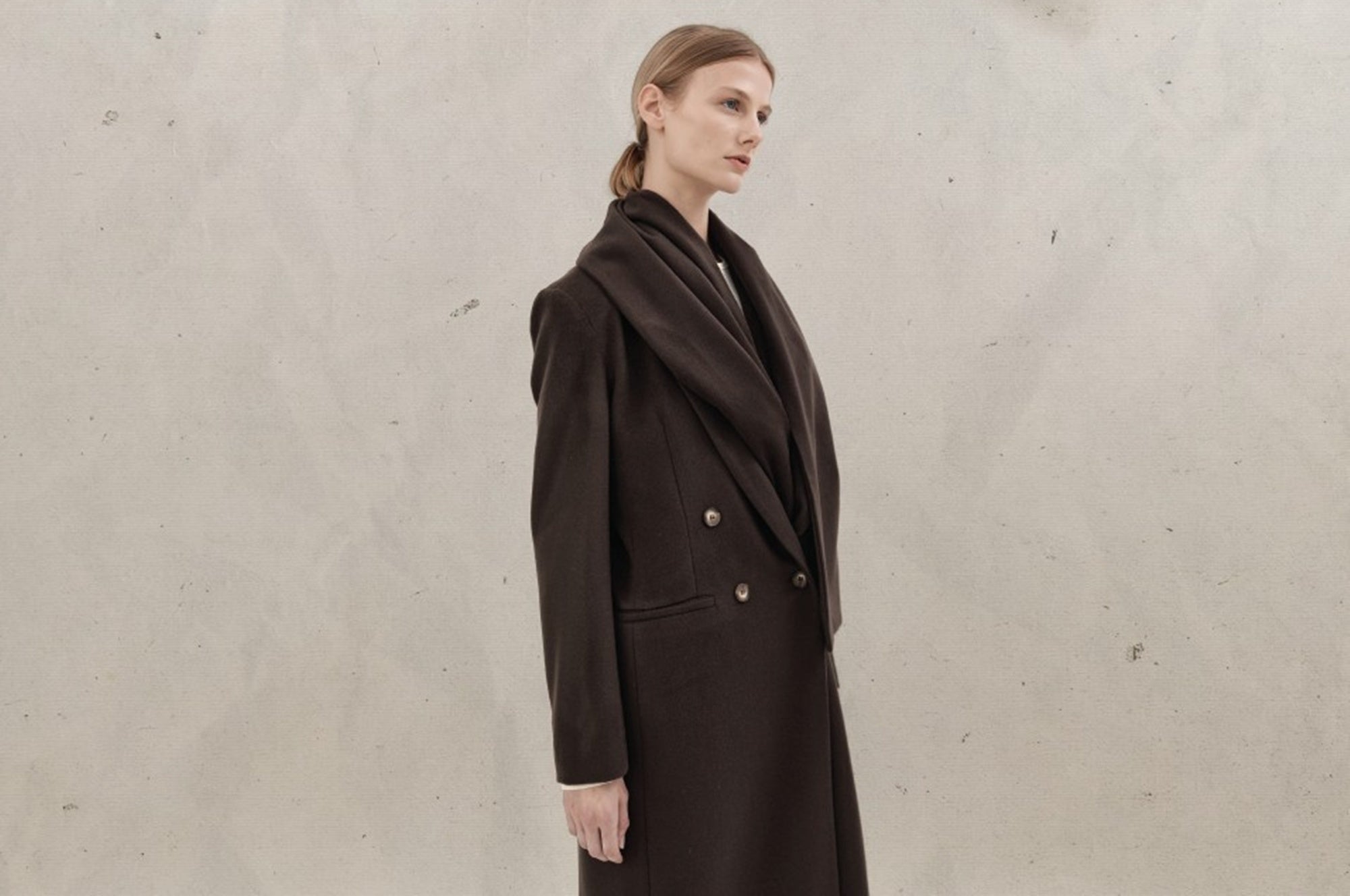 Woman wearing a brown coat against a plain background