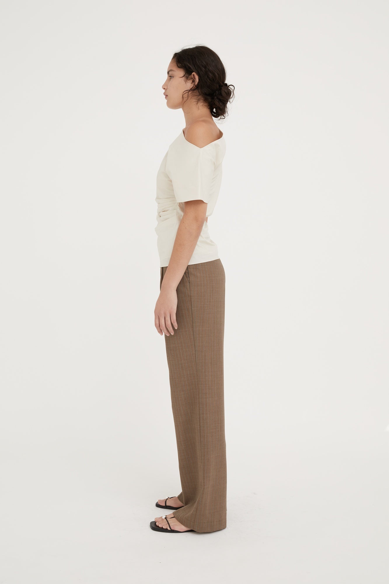 Woman wearing a white top and brown pants on a white background