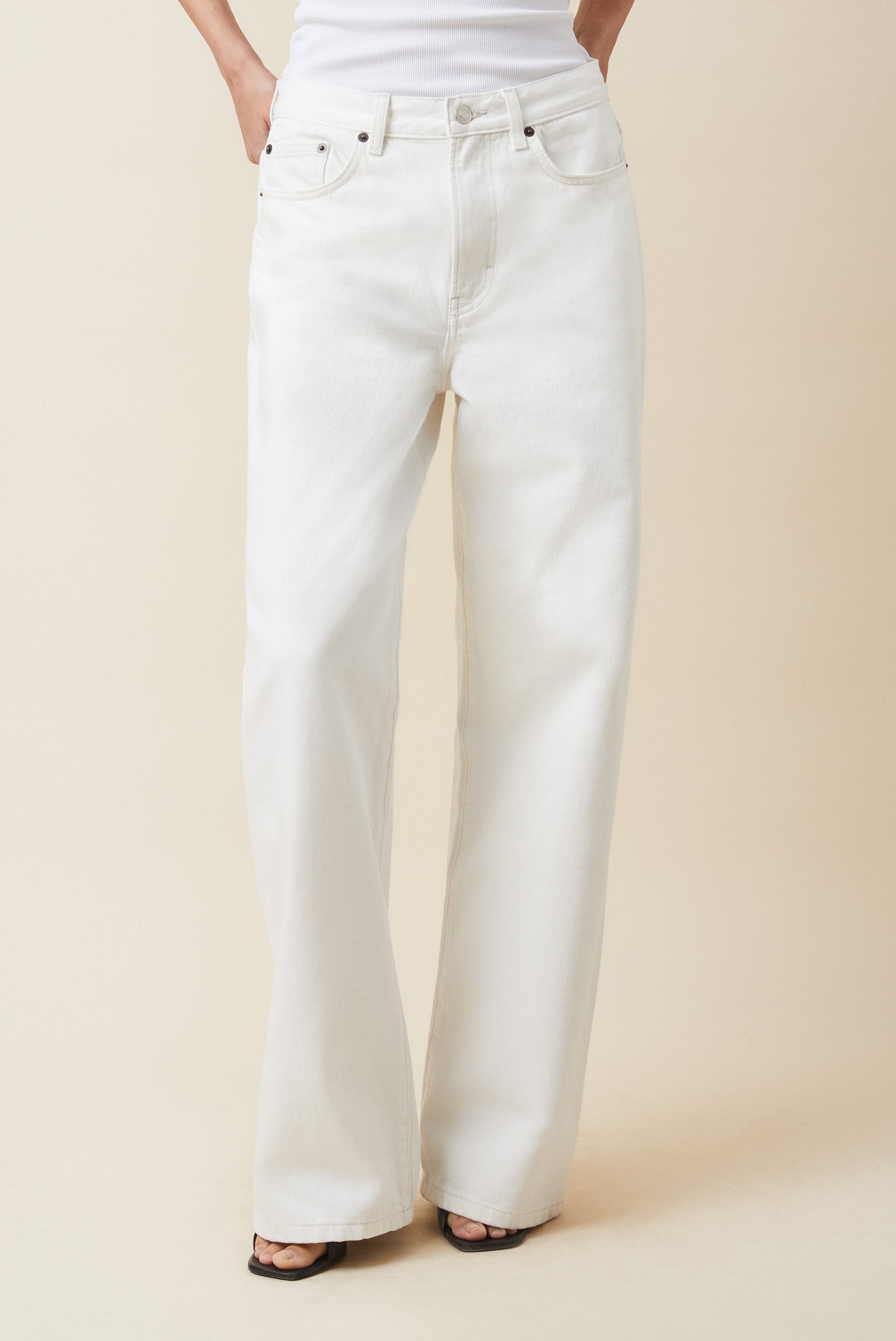 White jeans worn by a person on a beige background