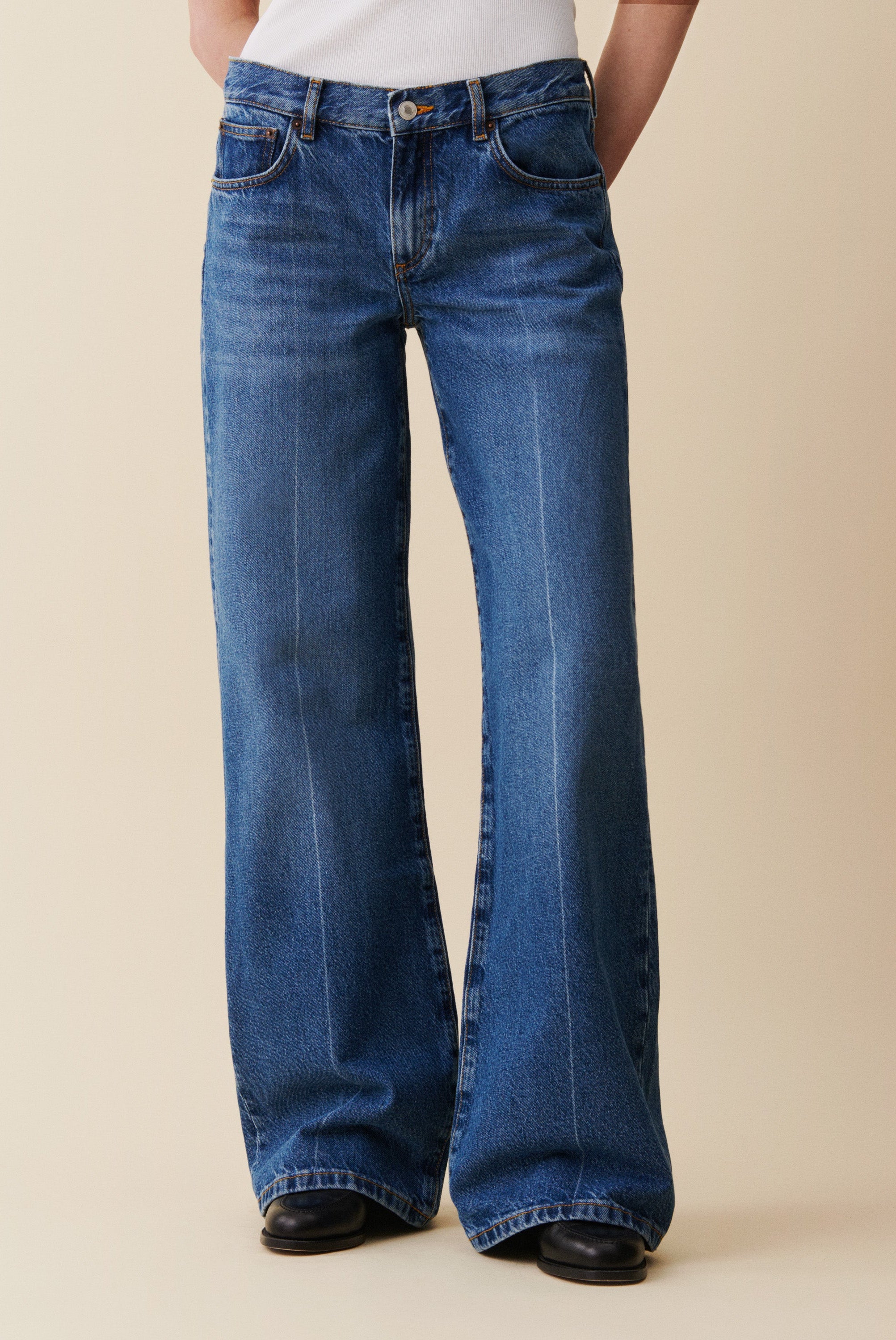 Blue jeans worn by a person on a beige background