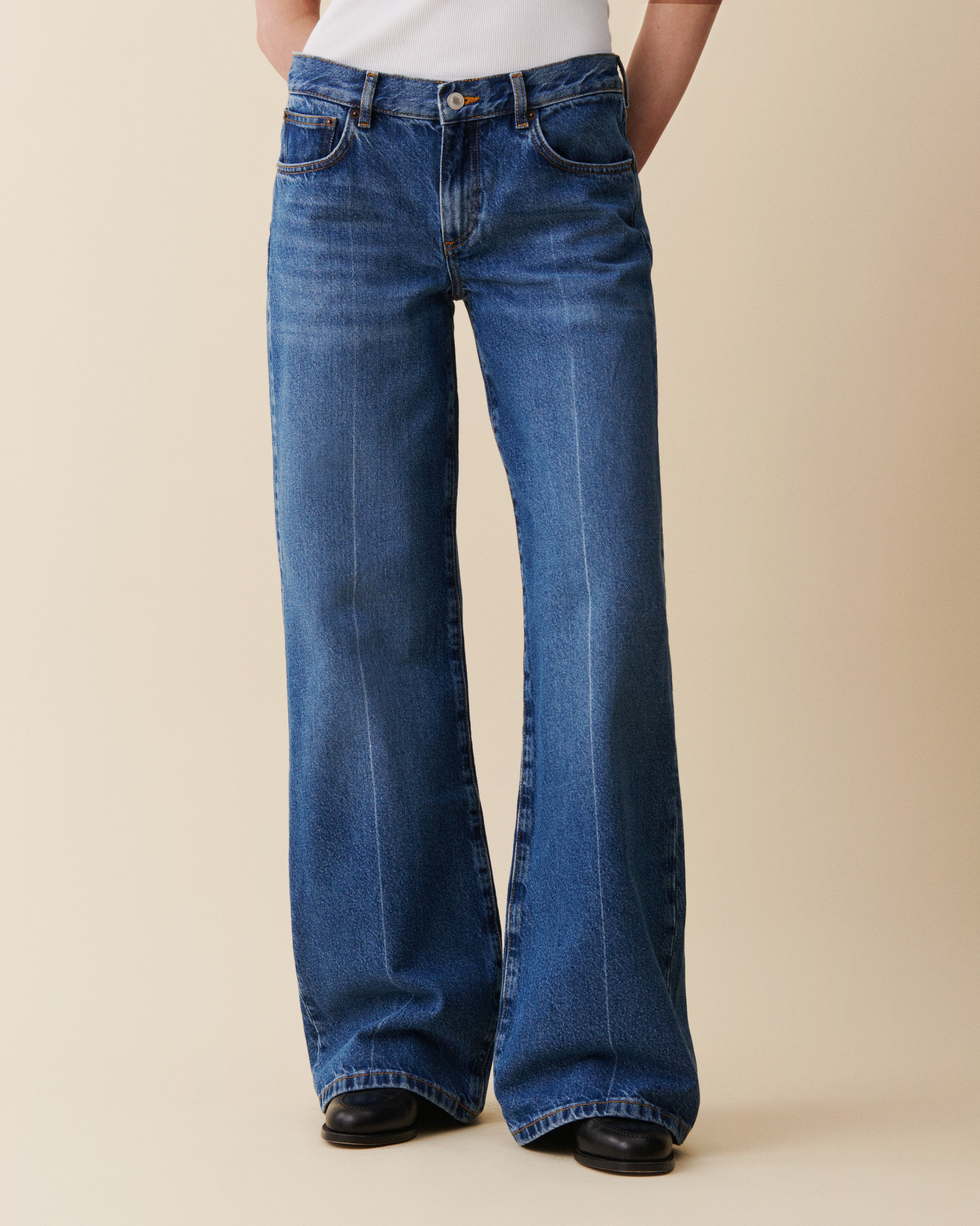 Blue jeans worn by a person on a beige background