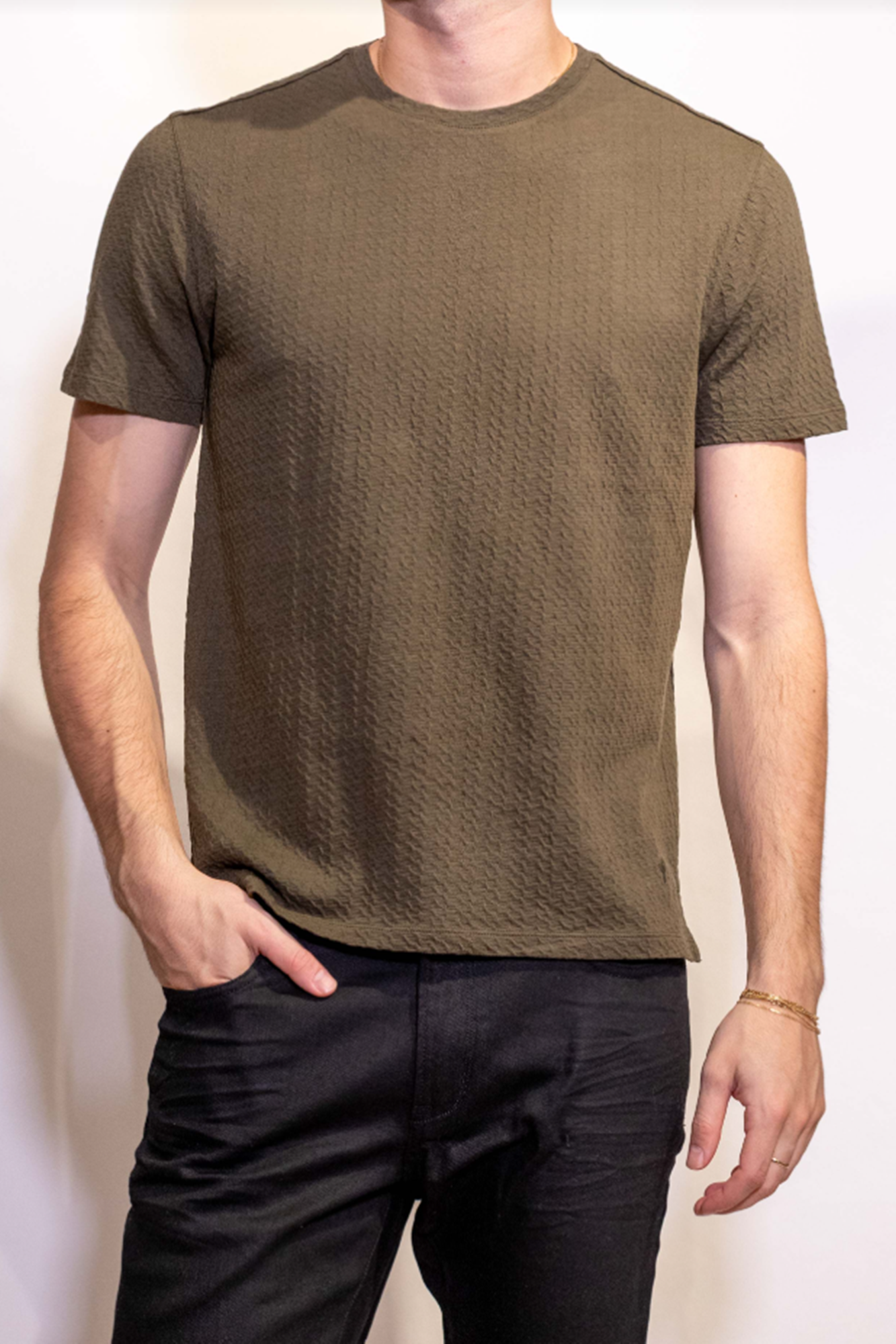 Person wearing a plain brown t-shirt and dark pants against a white background