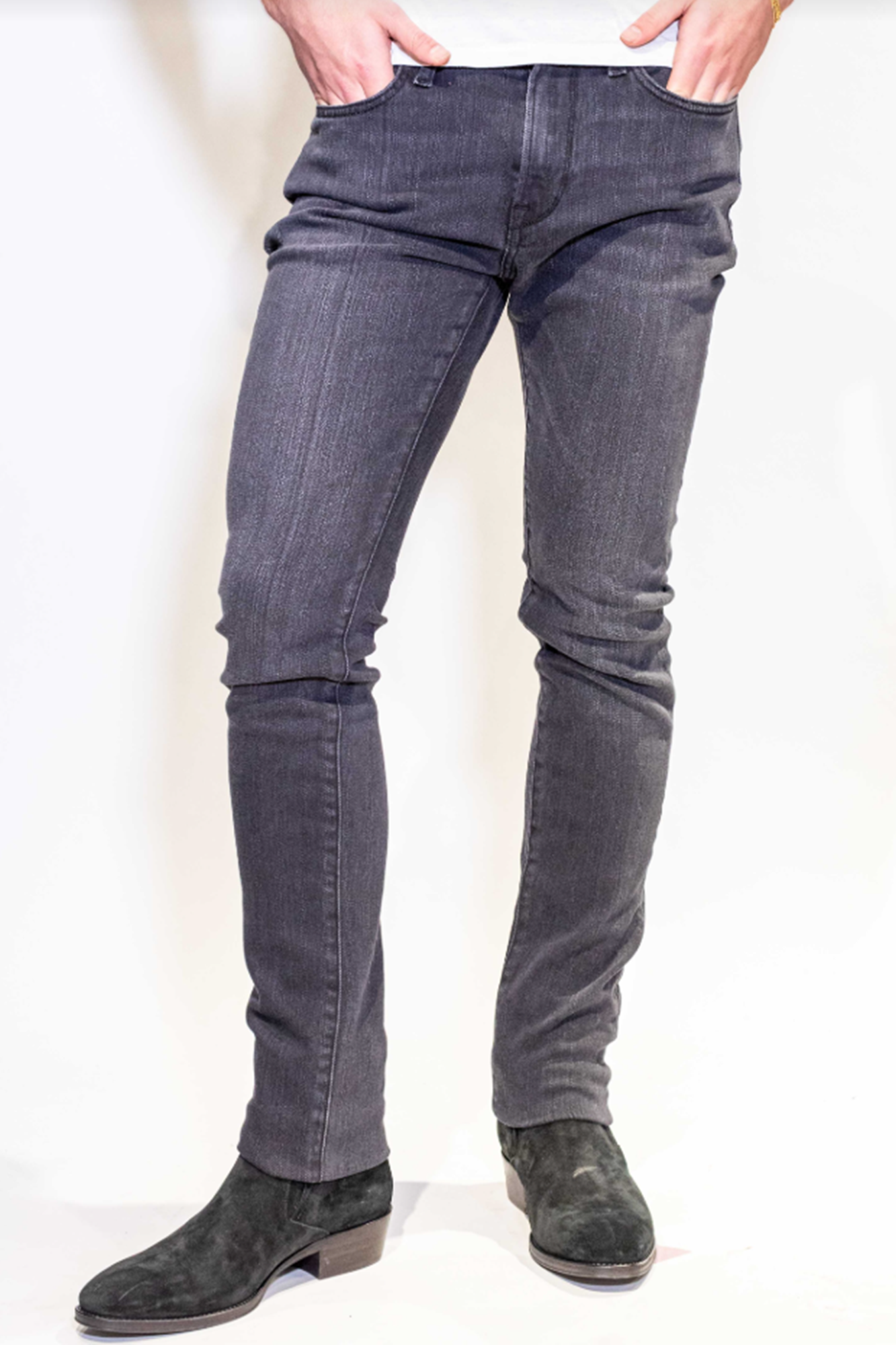 Person wearing dark gray jeans on a white background