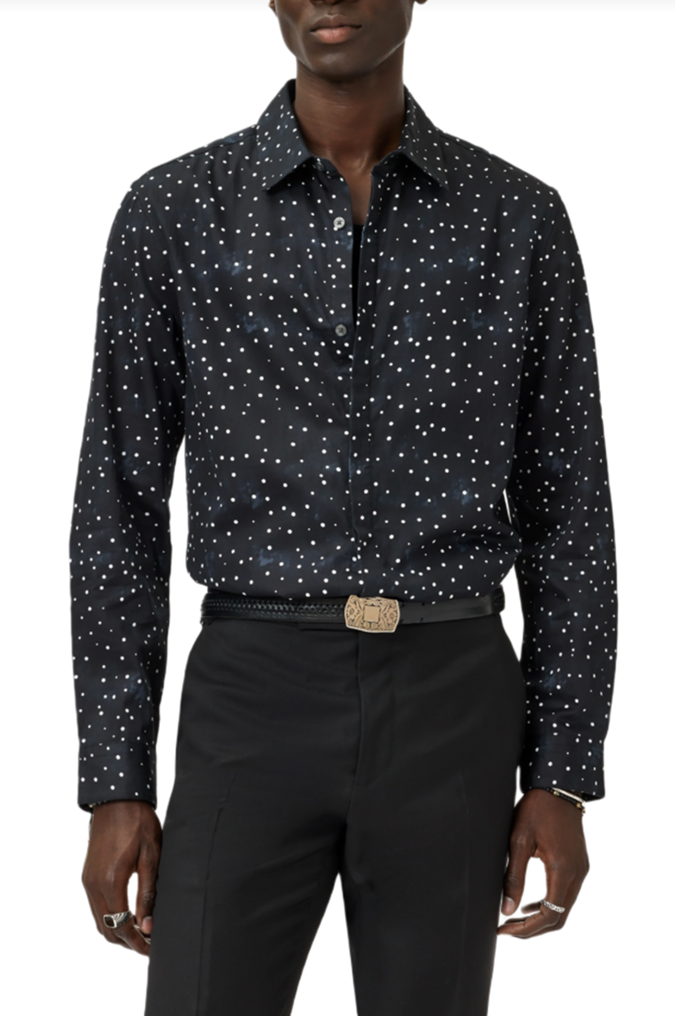 Man wearing a black patterned shirt and black pants on a white background