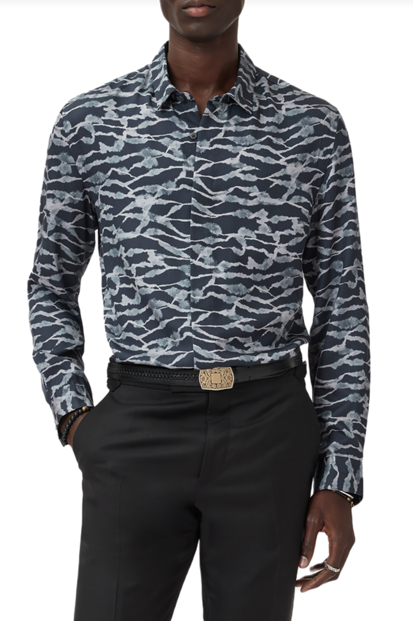 Person wearing a patterned shirt and black pants with a belt on a white background