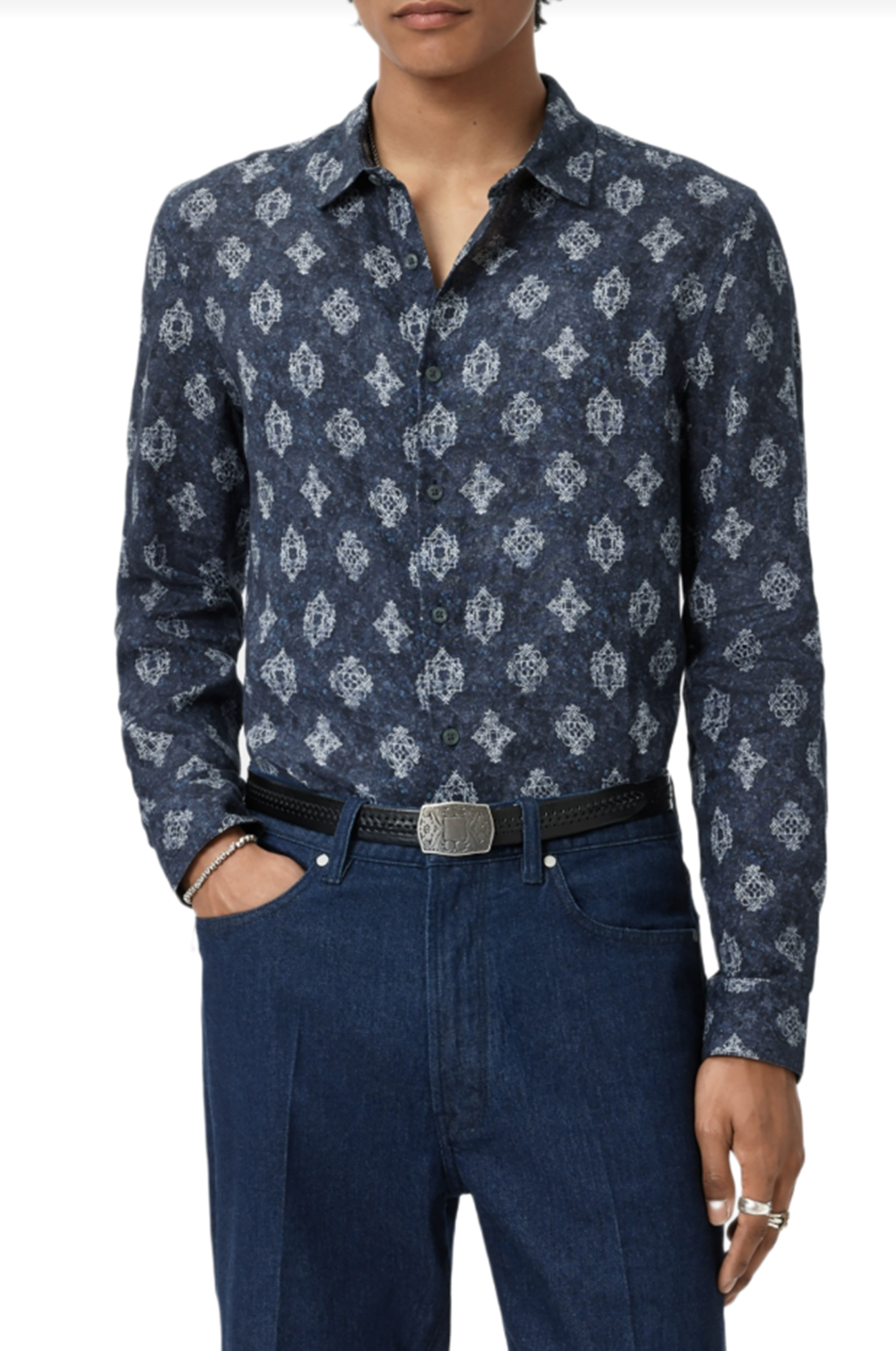 Person wearing a dark blue patterned shirt and jeans on a white background