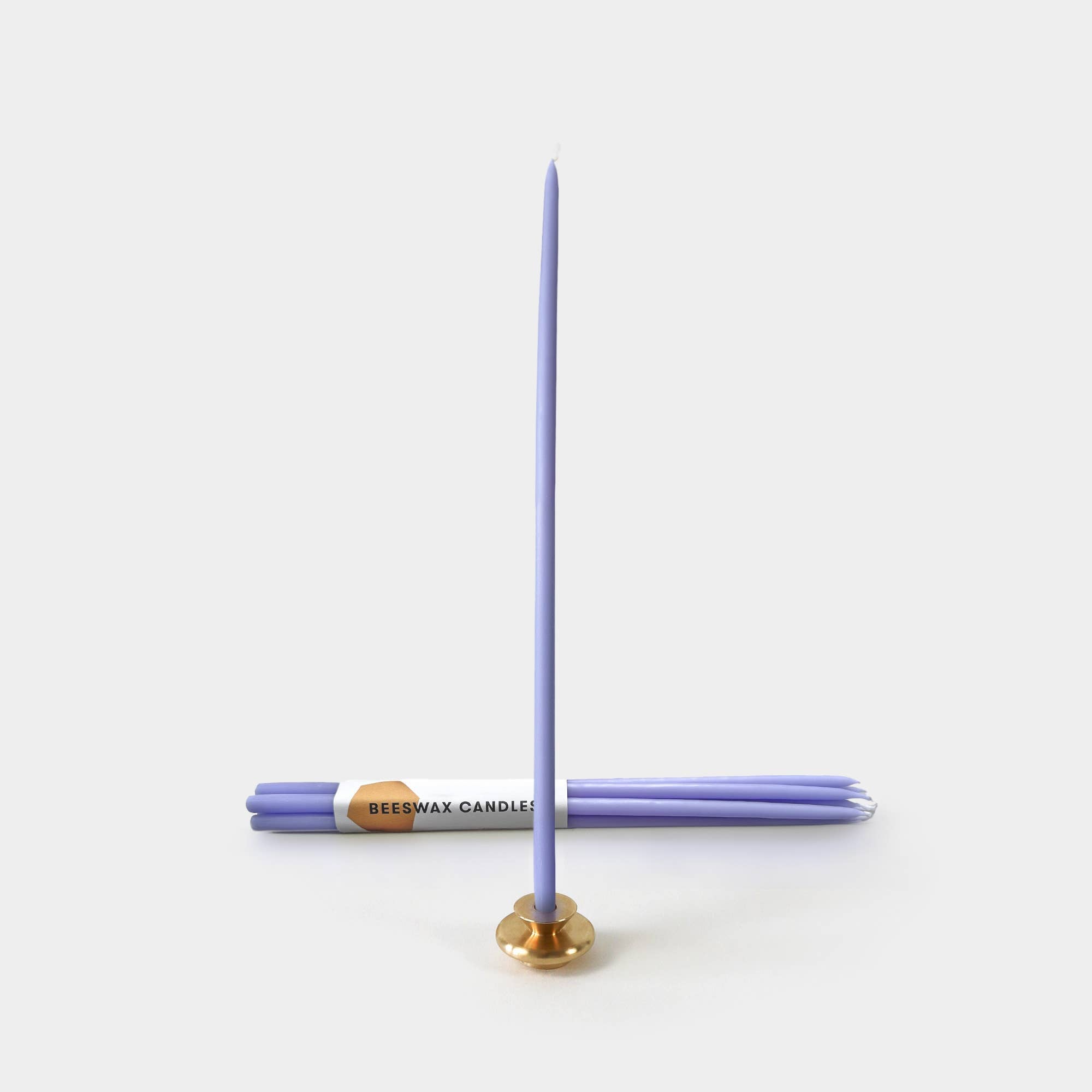 Purple candle on a white background with a gold base