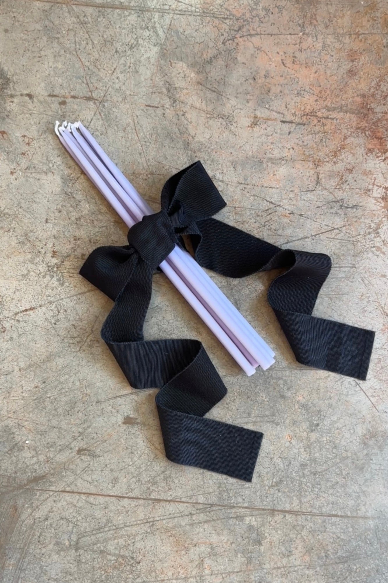White candles with black ribbons on a textured surface