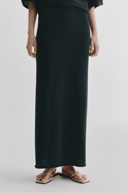 Person wearing a black long skirt on a plain background