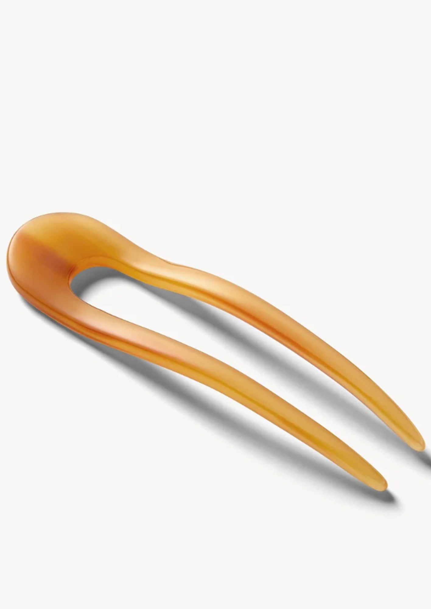 Cognac hair pin made of a light brown material on a white background