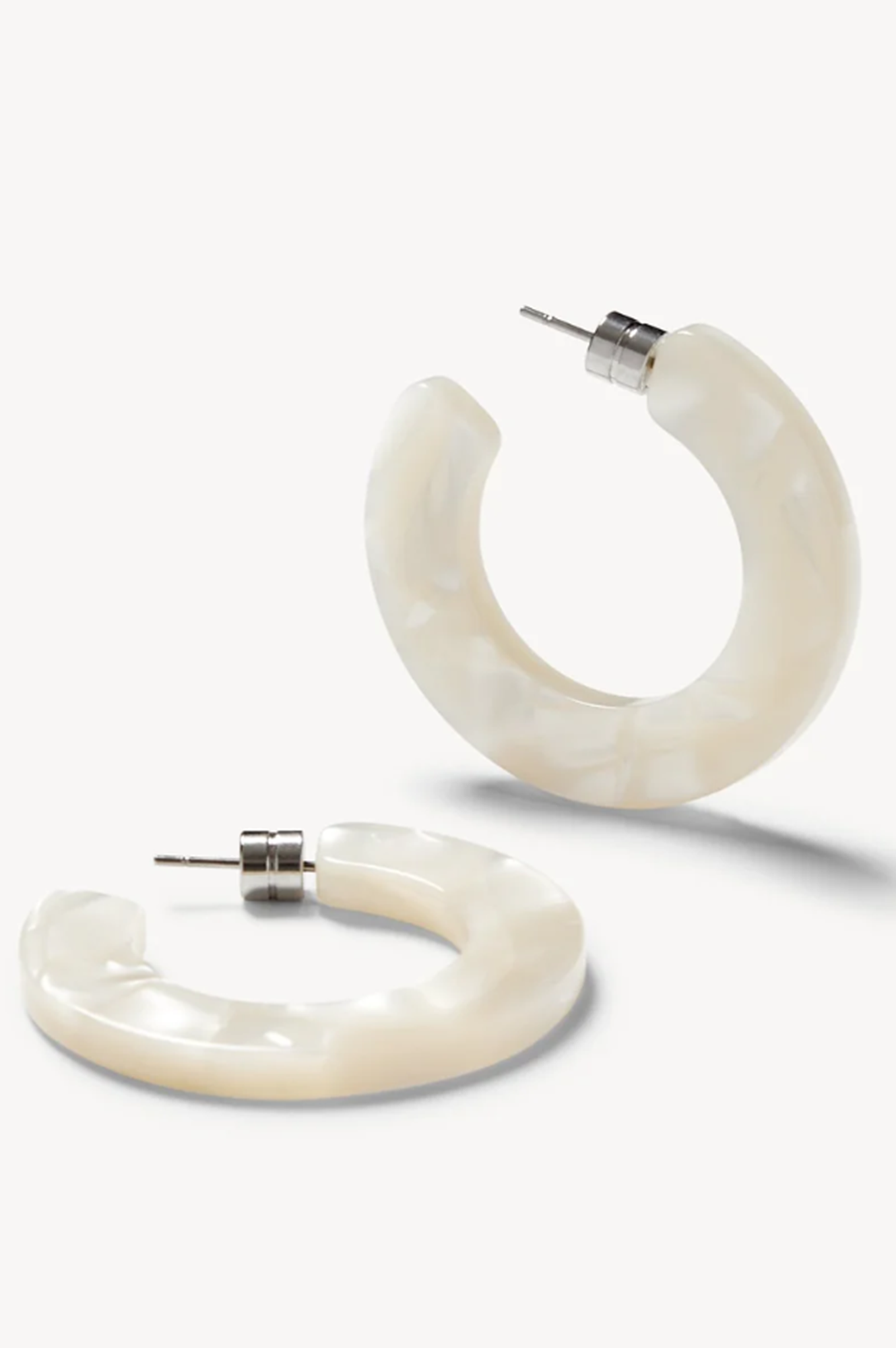 Pair of white sea shell hoop earrings on a white background