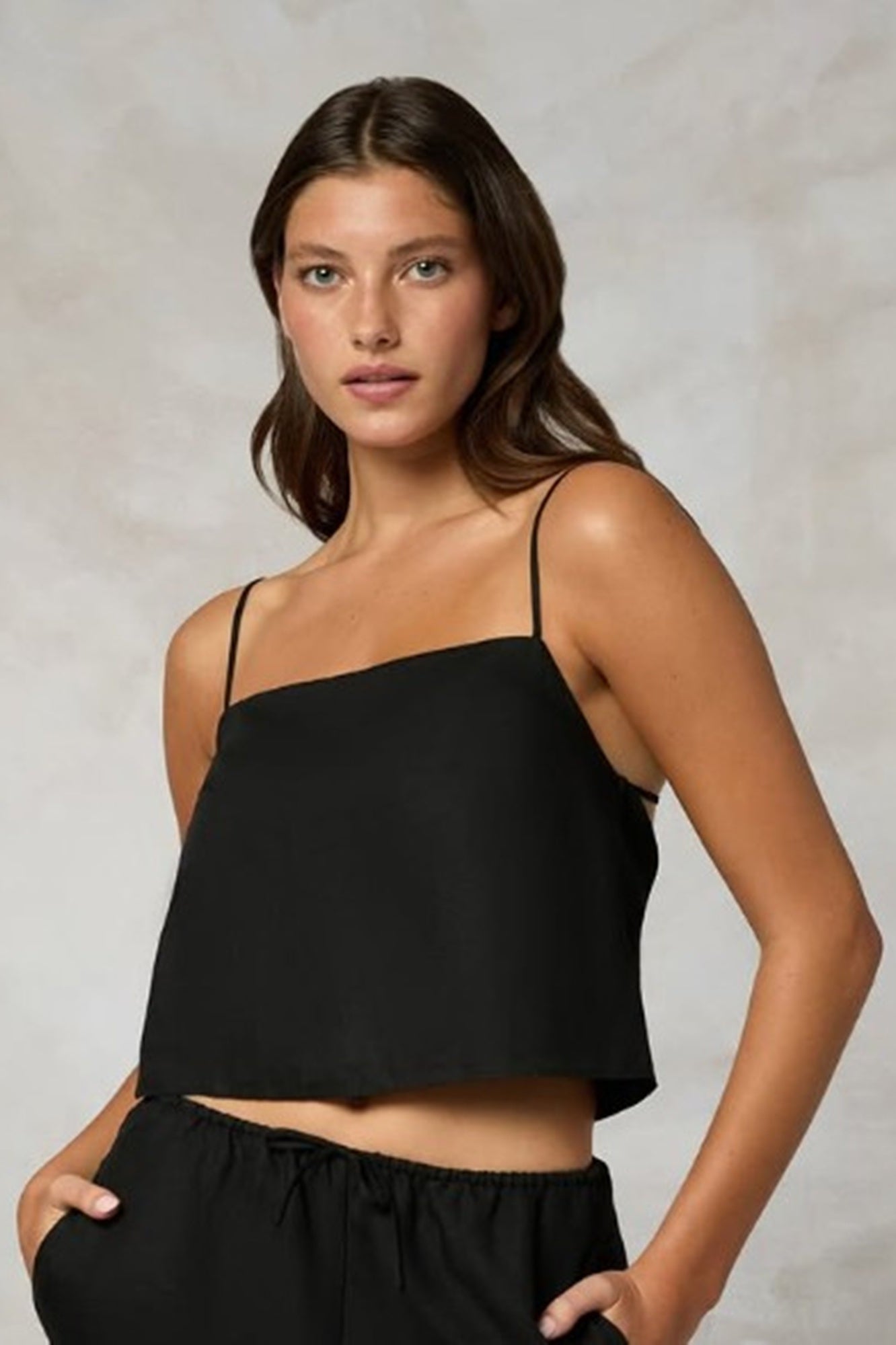 Woman wearing a black one-shoulder top against a neutral background