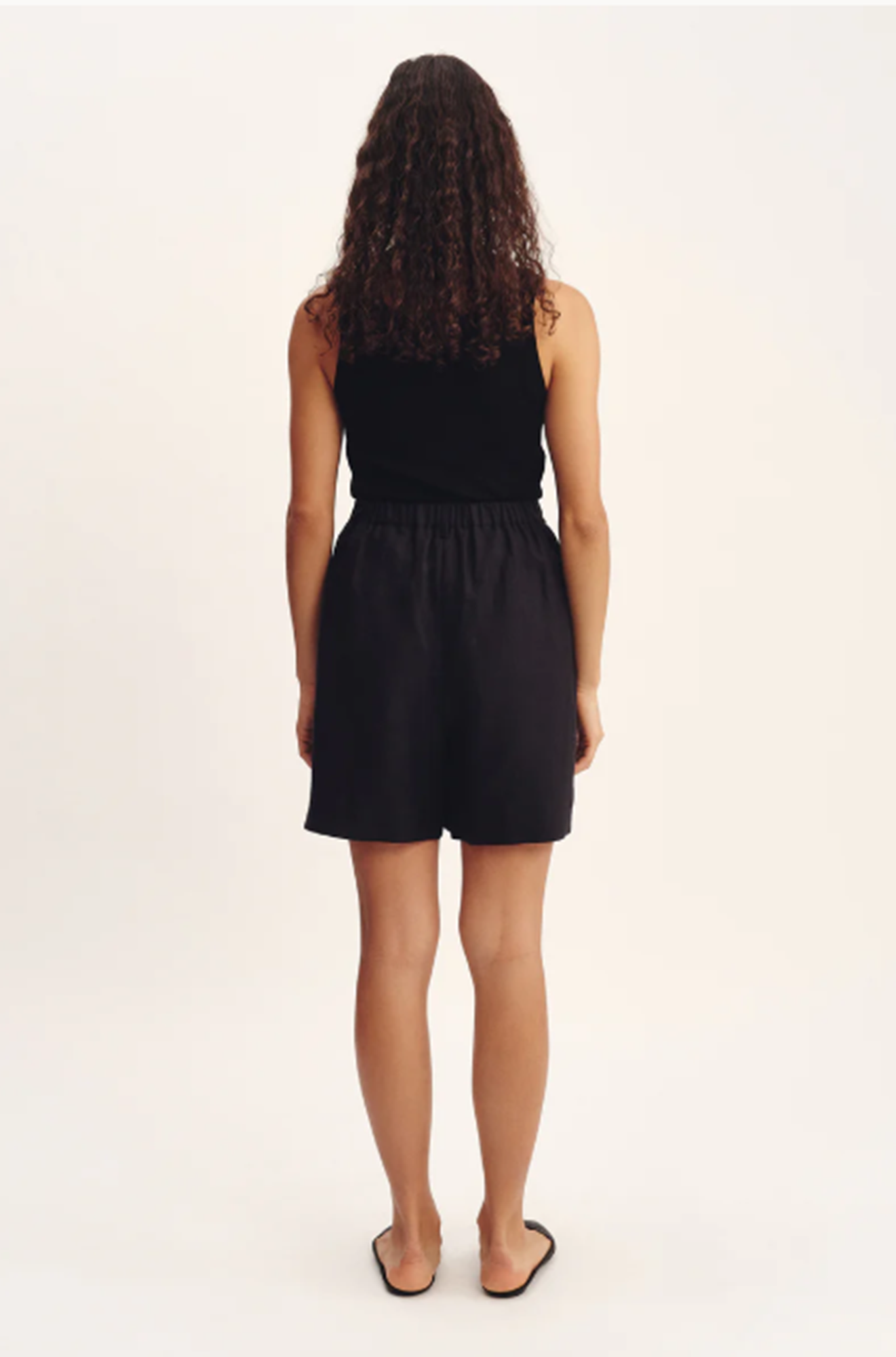 Woman wearing a black sleeveless top and shorts on a white background