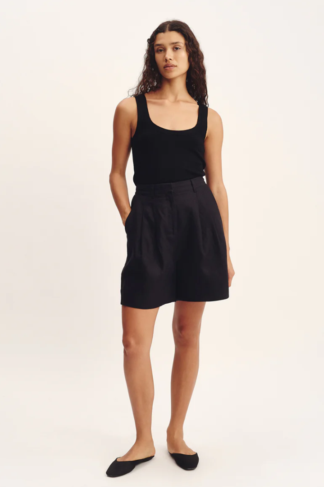 Woman wearing a black tank top and black shorts on a white background
