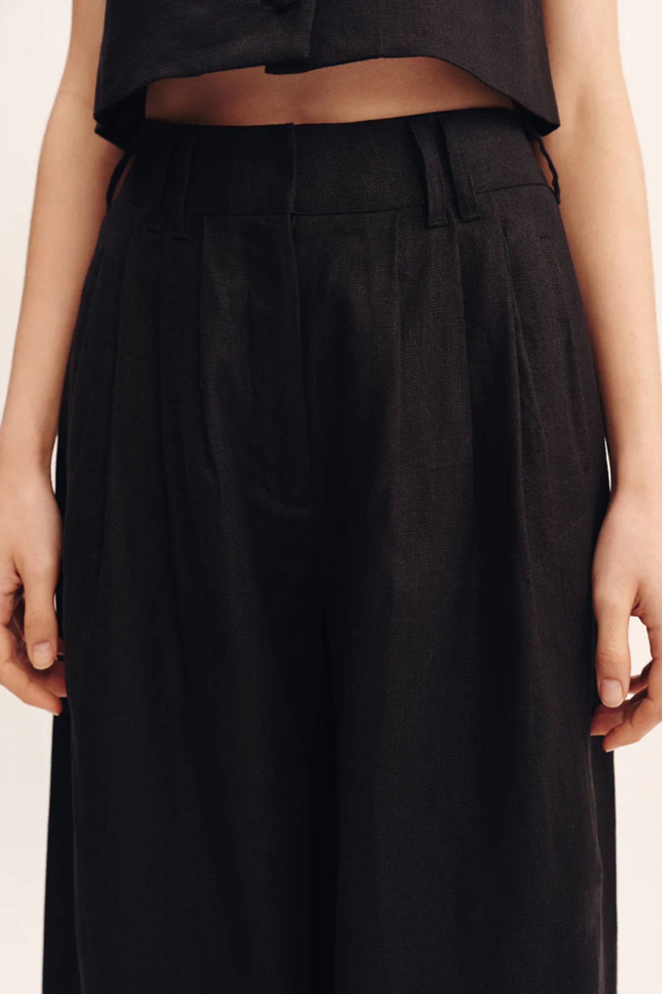 Black trousers worn by a person on a plain background