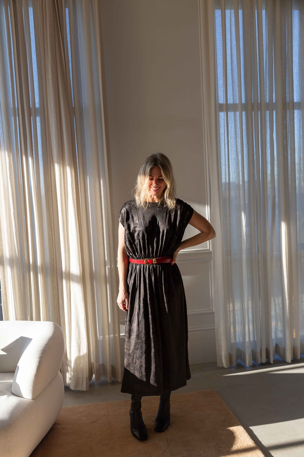 by Malene Birger Zoilo Belt in Red Dahlia belting a dark jacquard midi dress, full-length view in a sunlit loft