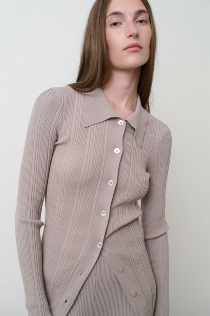 Woman wearing a ribbed knit cardigan with a plain background