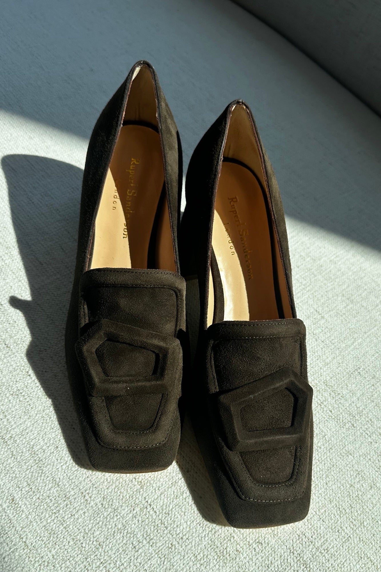 Pair of dark brown loafers on a light surface with a neutral background